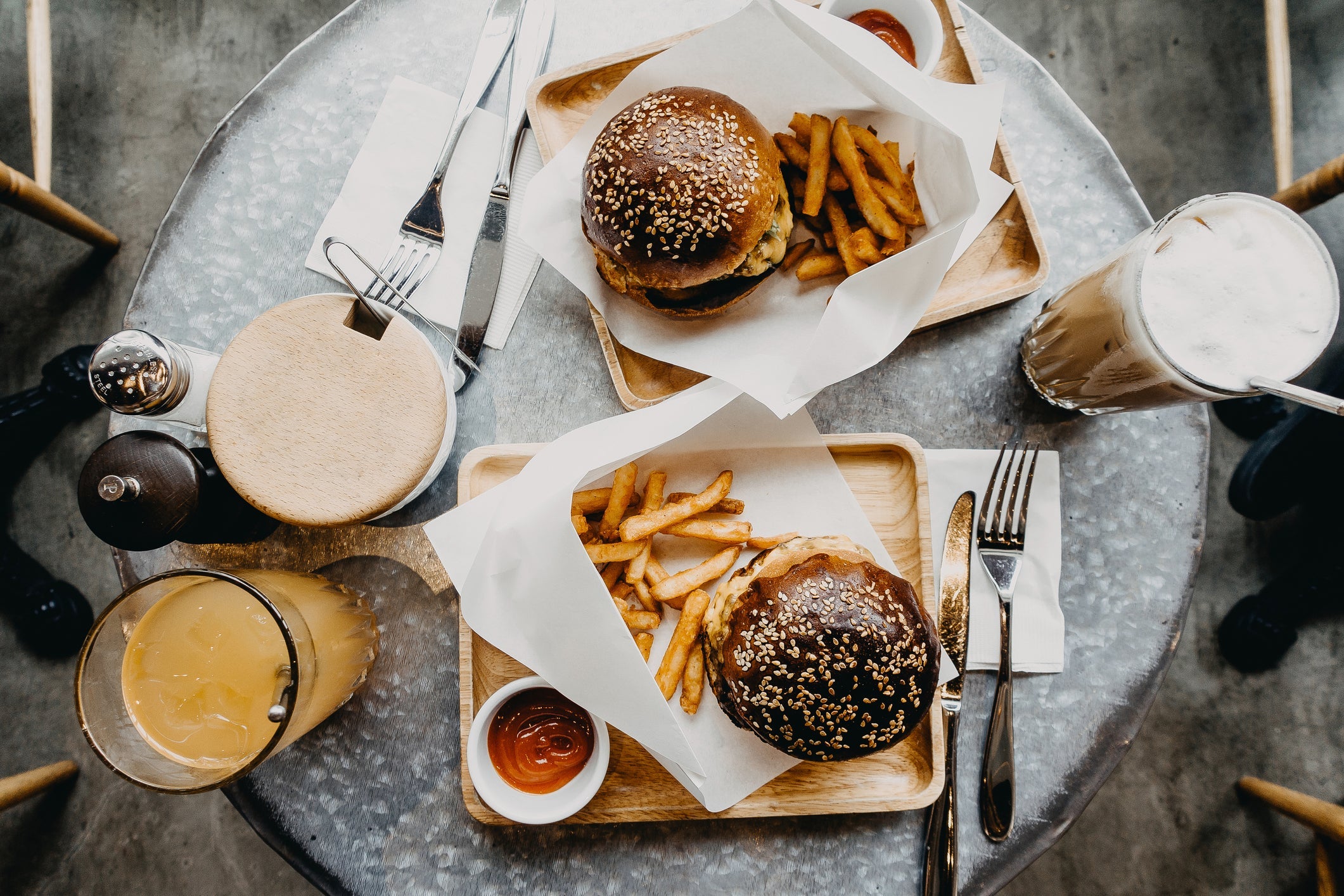 Top view of burgers with french fries and drinks freshly served on table in cafe