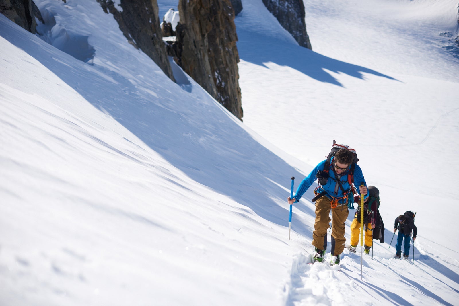 Group of 3 people ski touring up hill