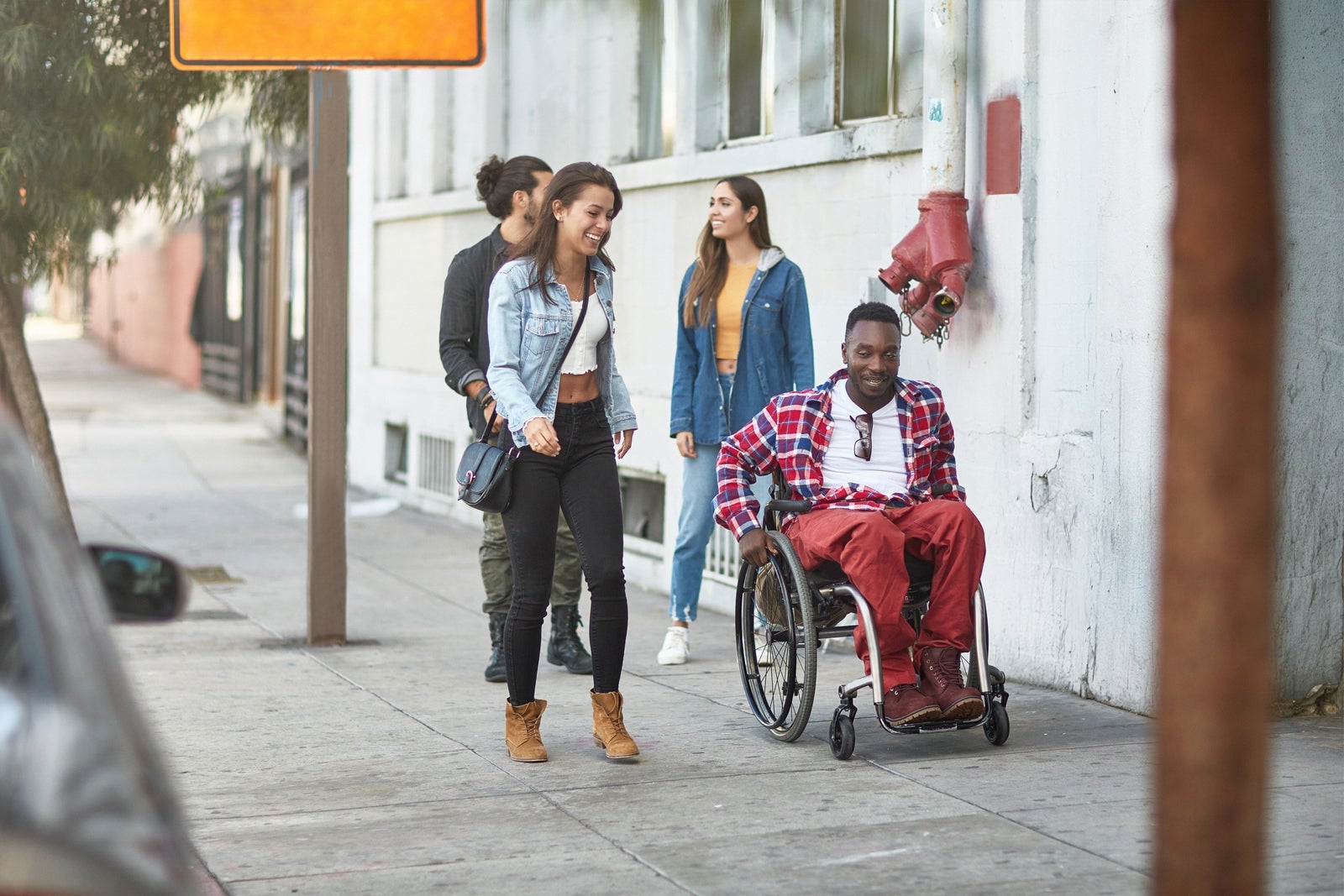 Friends walking with disabled man on sidewalk