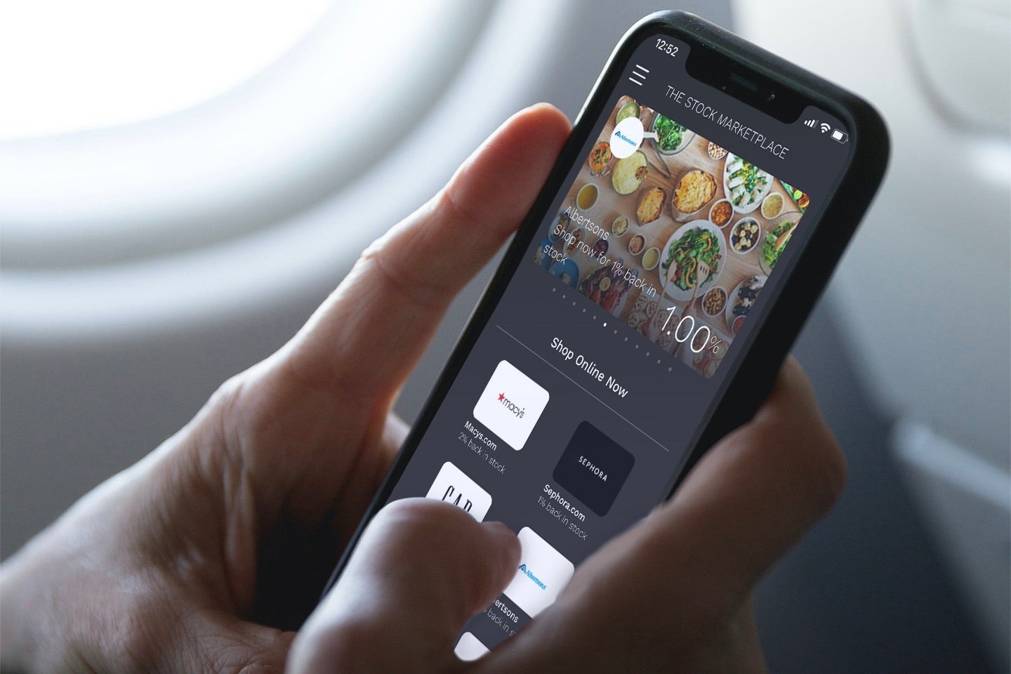 Person_holding_smartphone_with_stock_marketplace_showing_albertsons_landscape