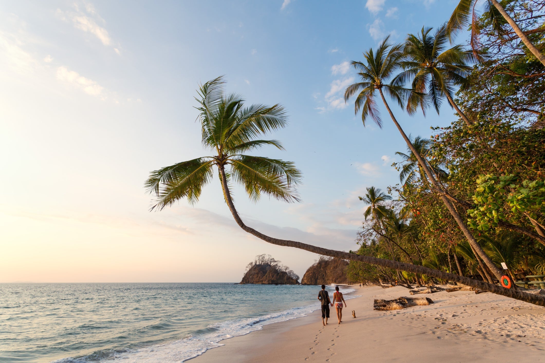 Couple of tourists walking on exotic beach at sunset, Costa Rica