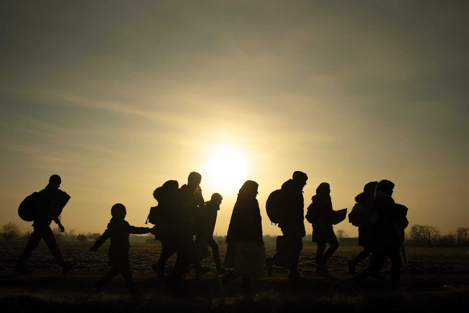 Migrants walking at sunset