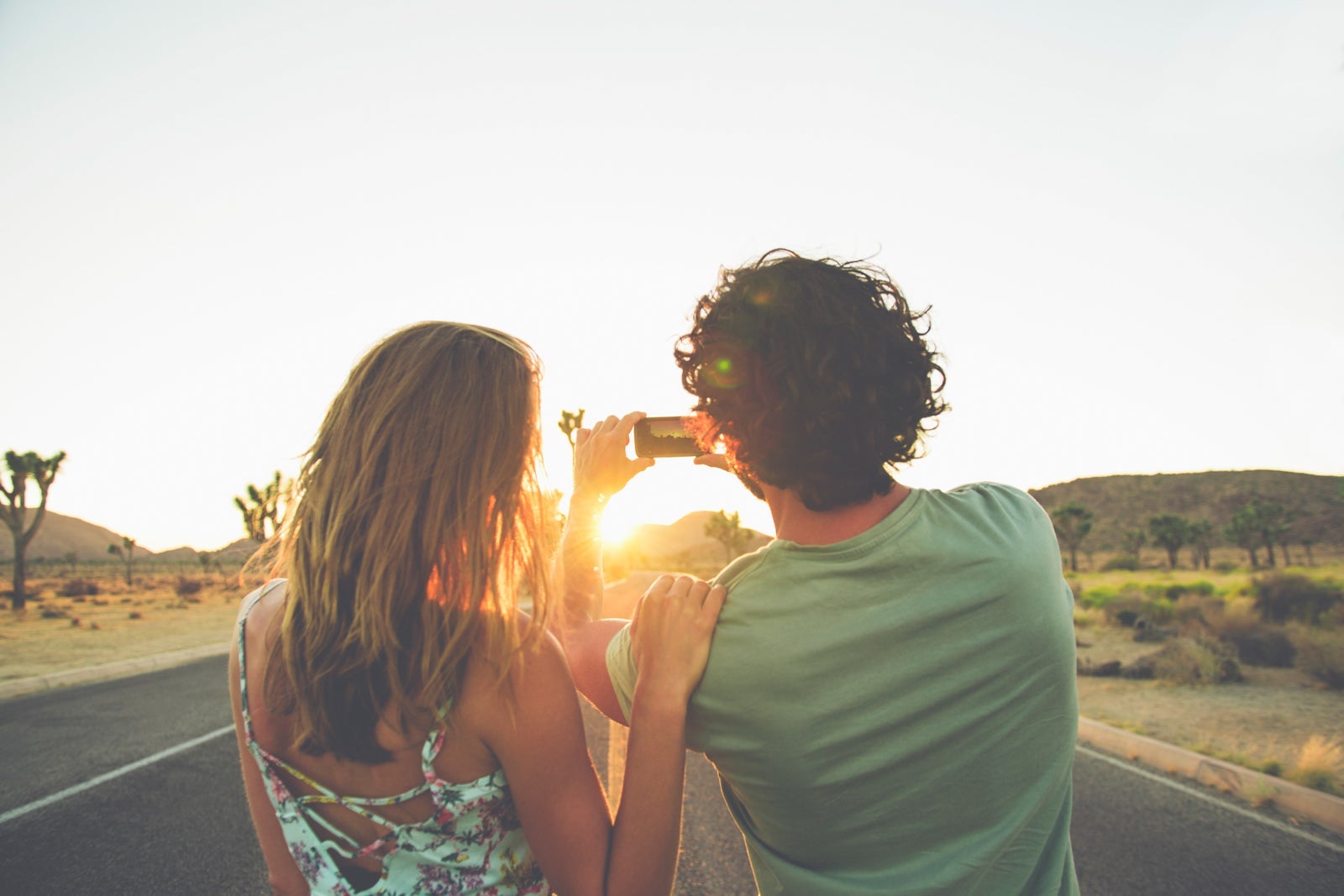 Hispanic couple photographing sunset in street