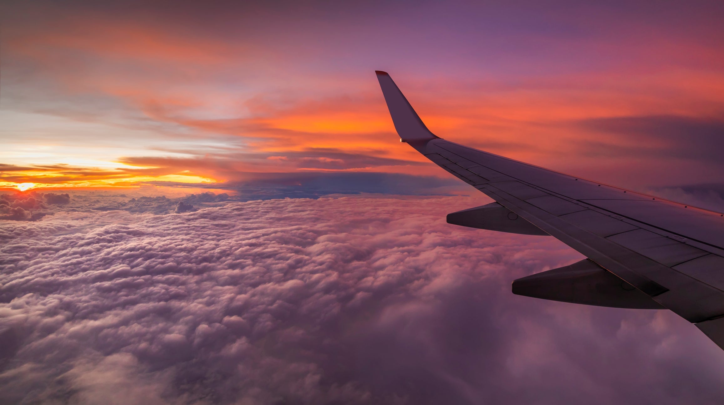 View from the airplane window on a beautiful sunset above the clouds.