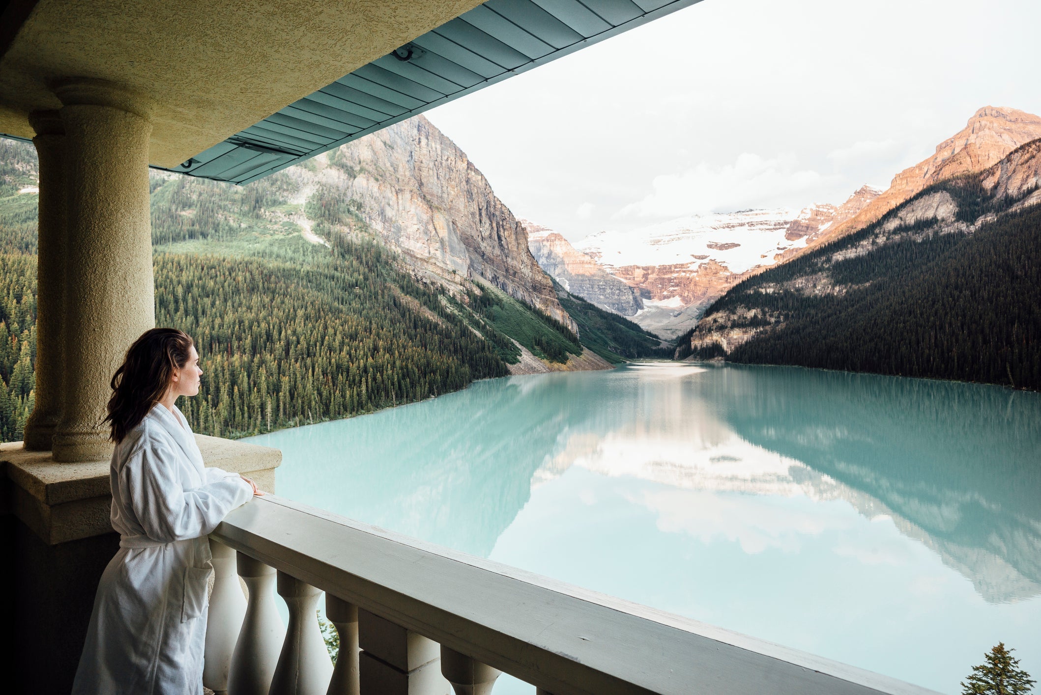 Young woman in bathrobe overlooking Lake Louise from balcony