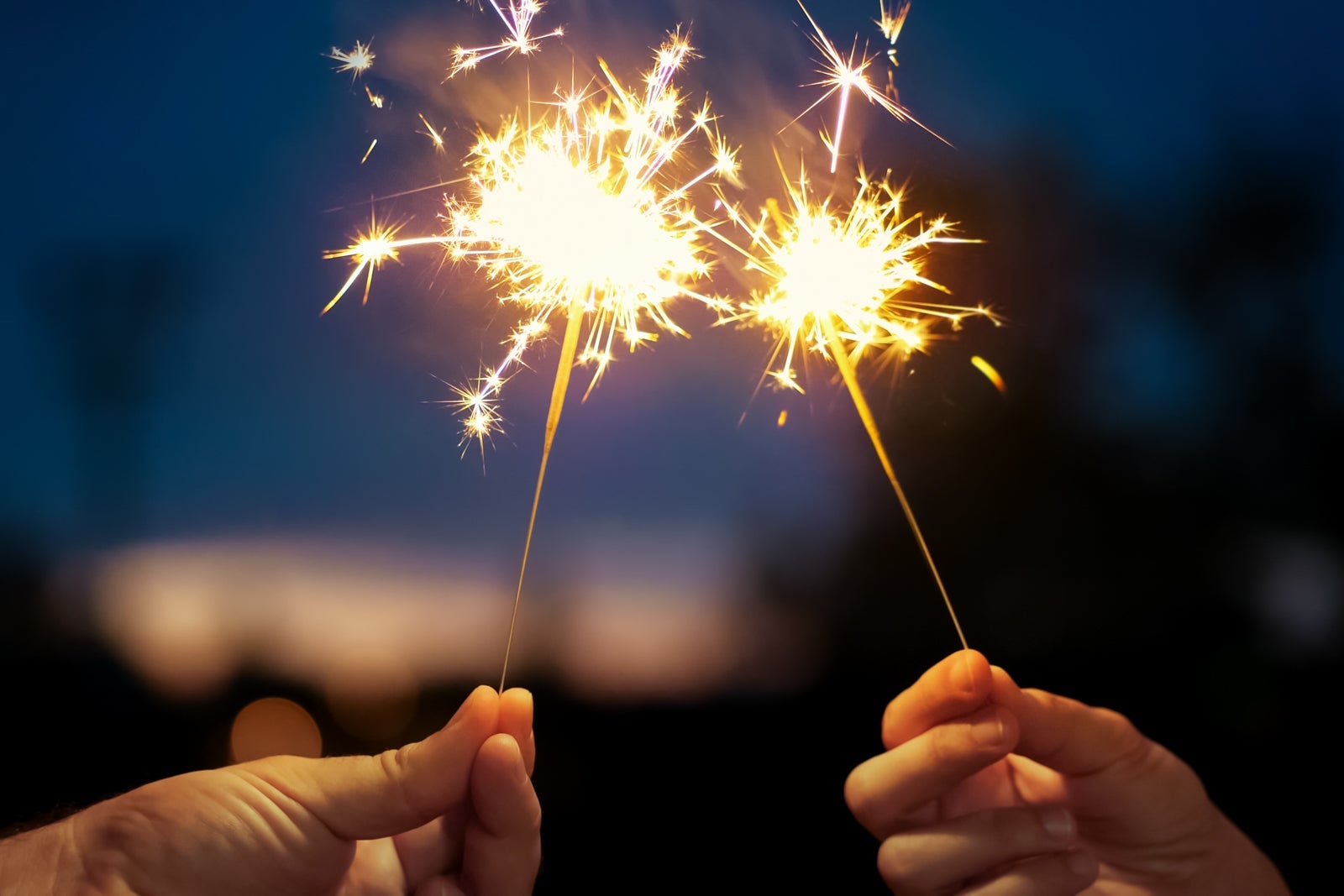 Hand Holding Firework Display At Night