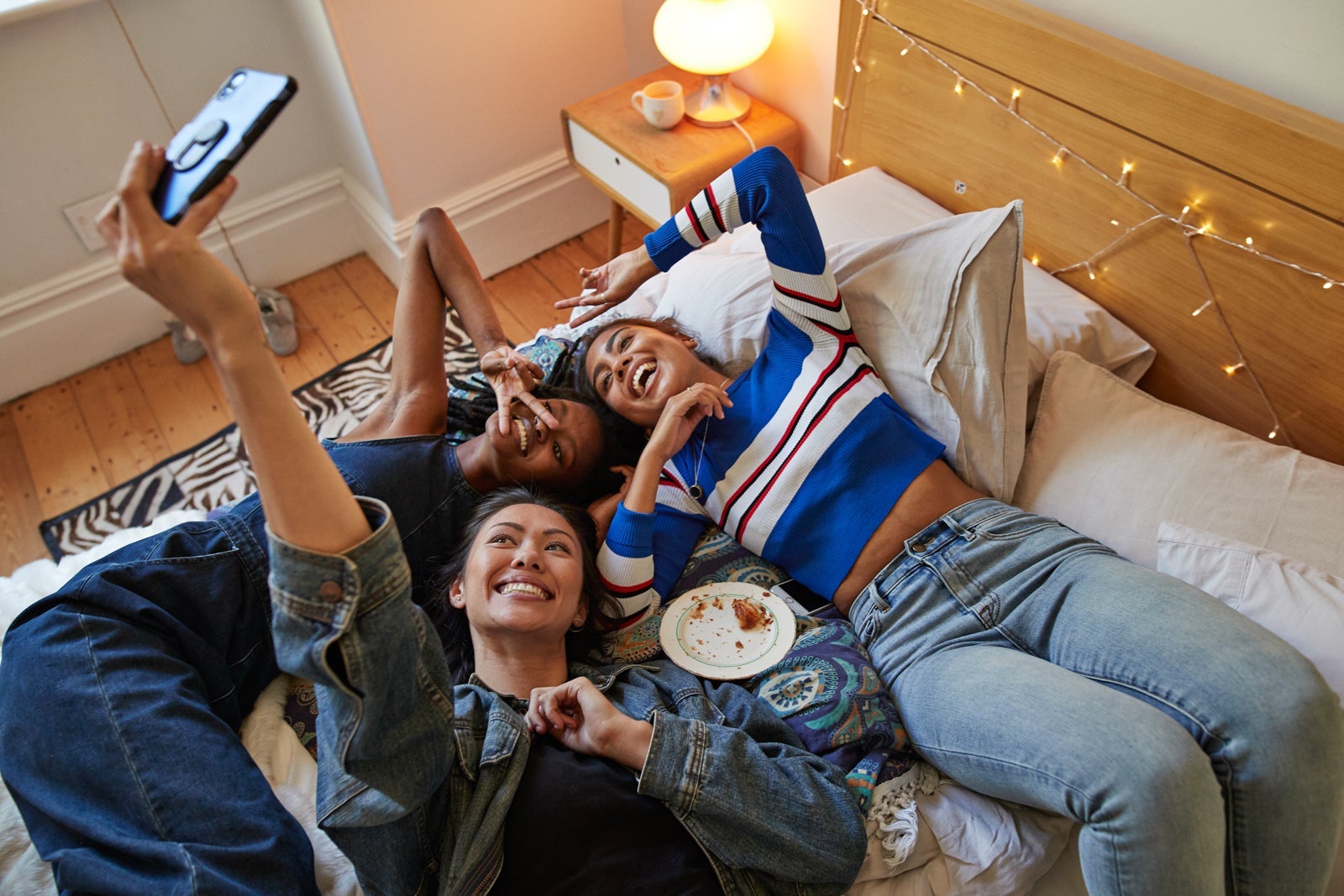 Friends taking selfie while lying on bed