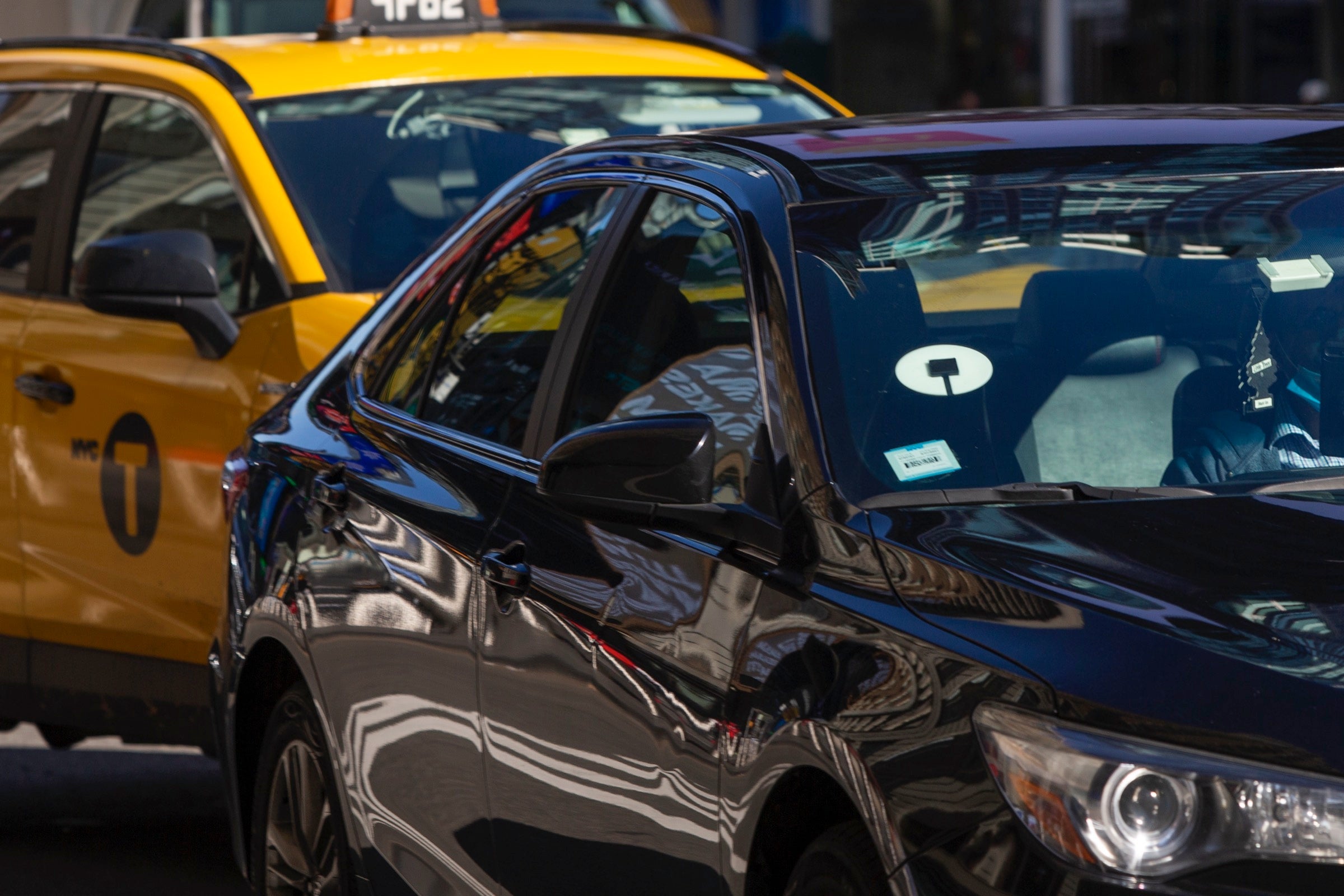Uber driving in front of a taxi in New York City