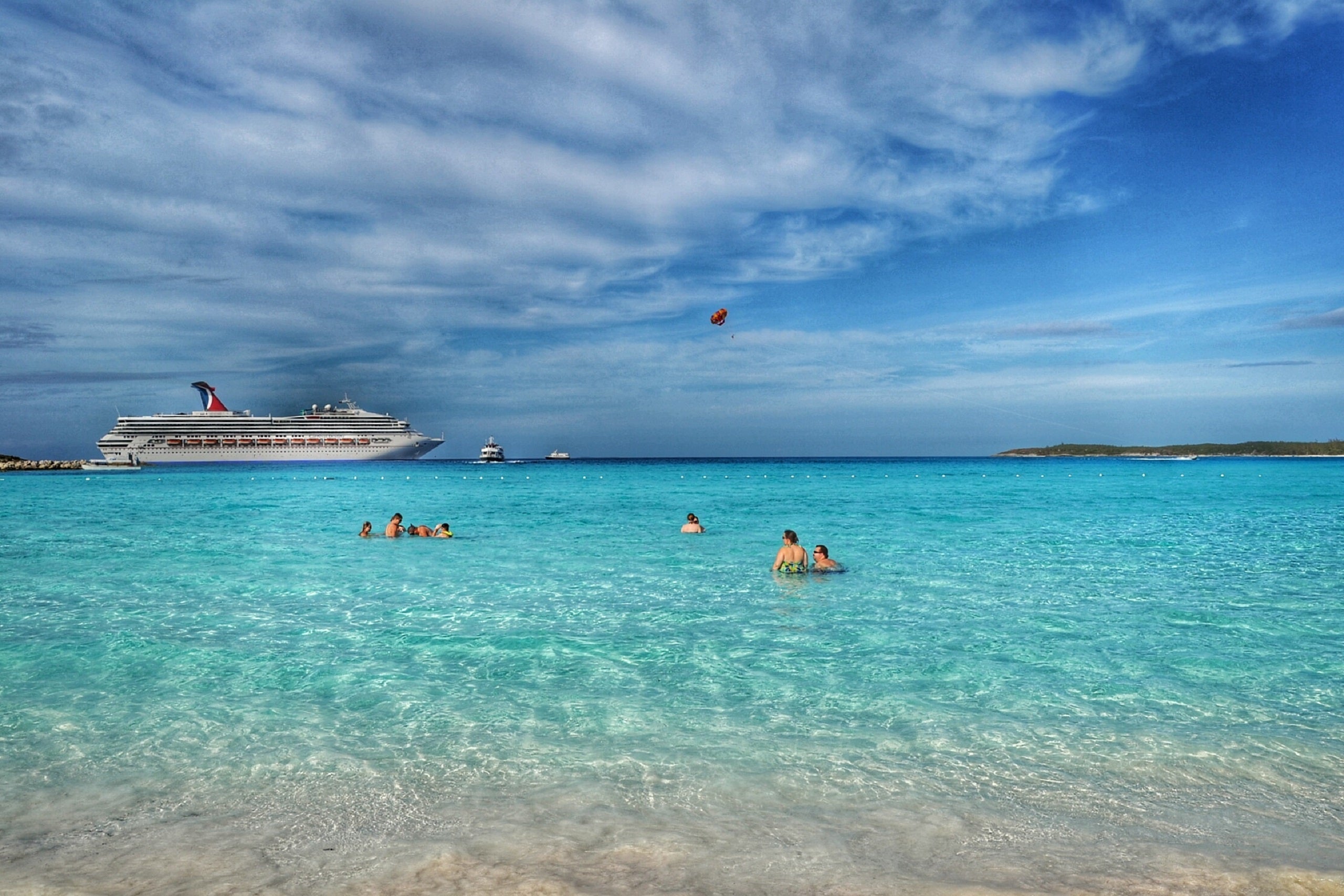 People In Sea By Cruise Ship Against Sky