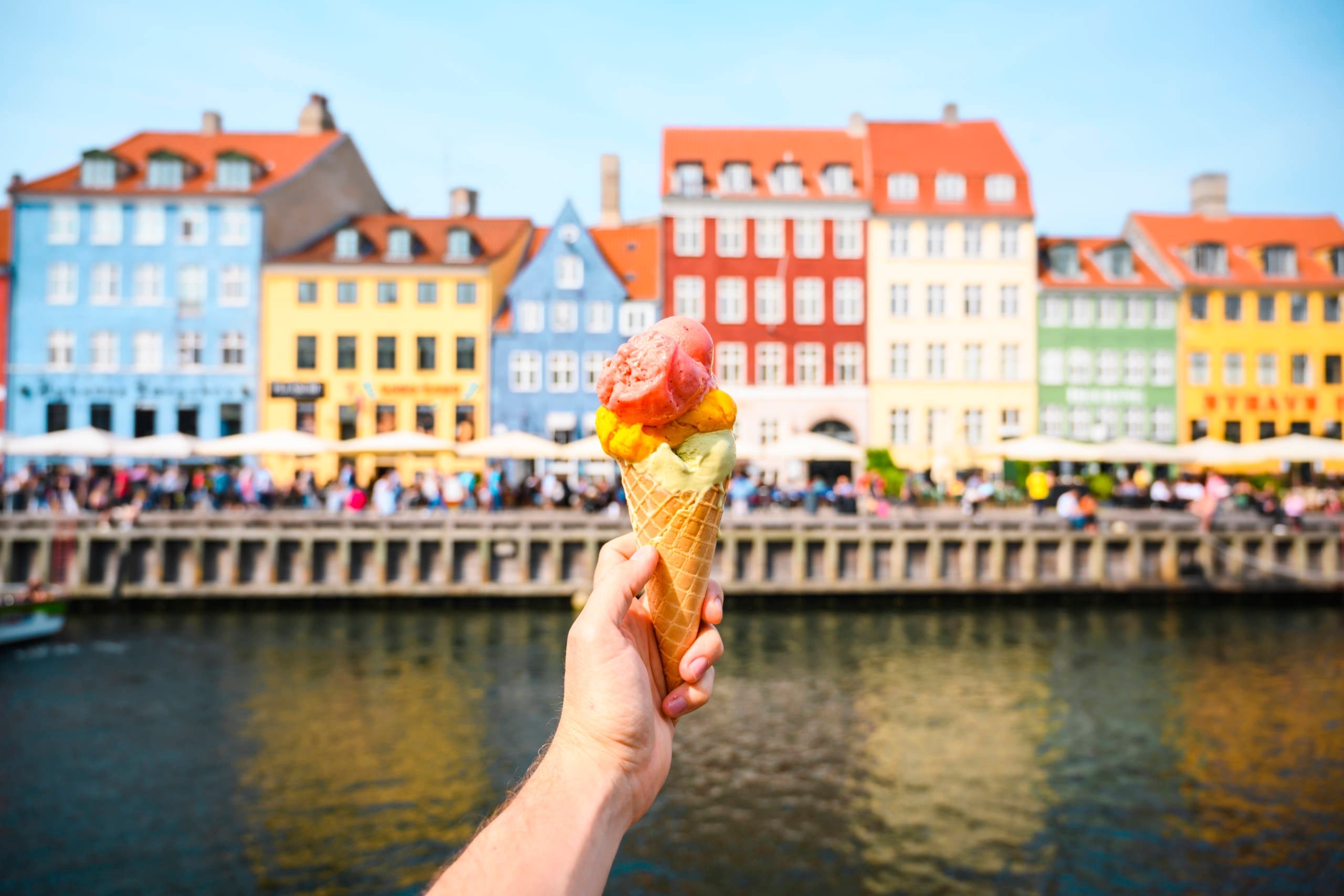Personal perspective of tourist holding an ice cream in front of Nyhavn canal, Copenhagen