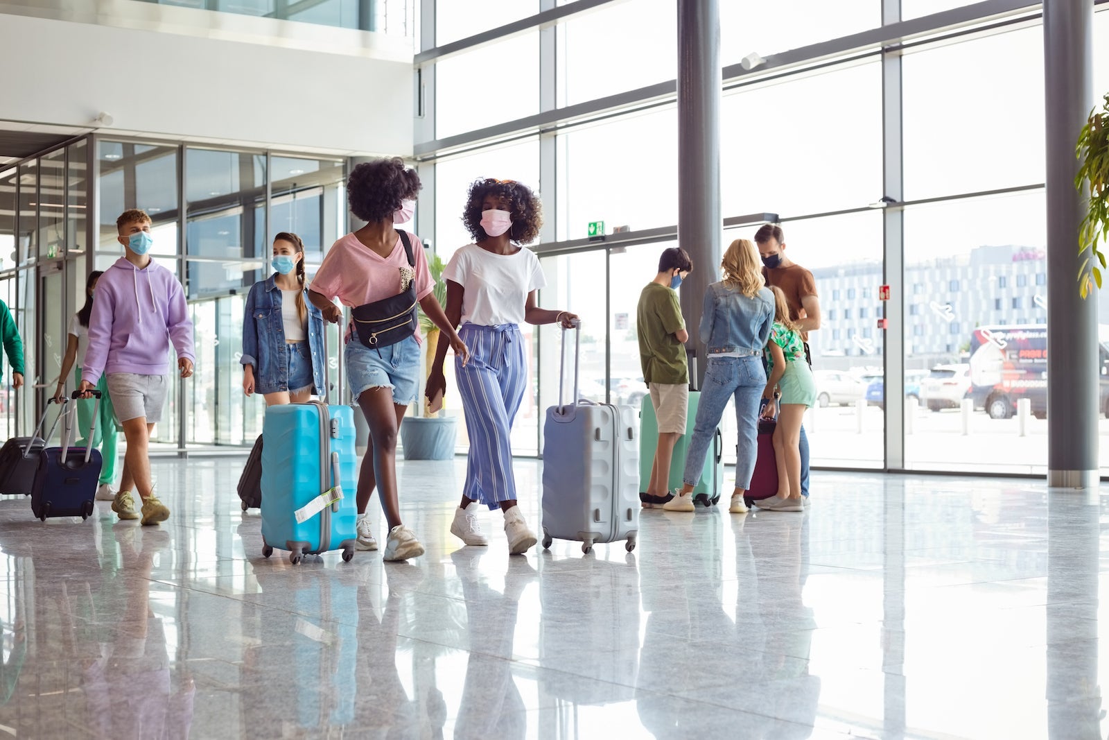 Passengers at the airport with luggage, wearing N95 face masks