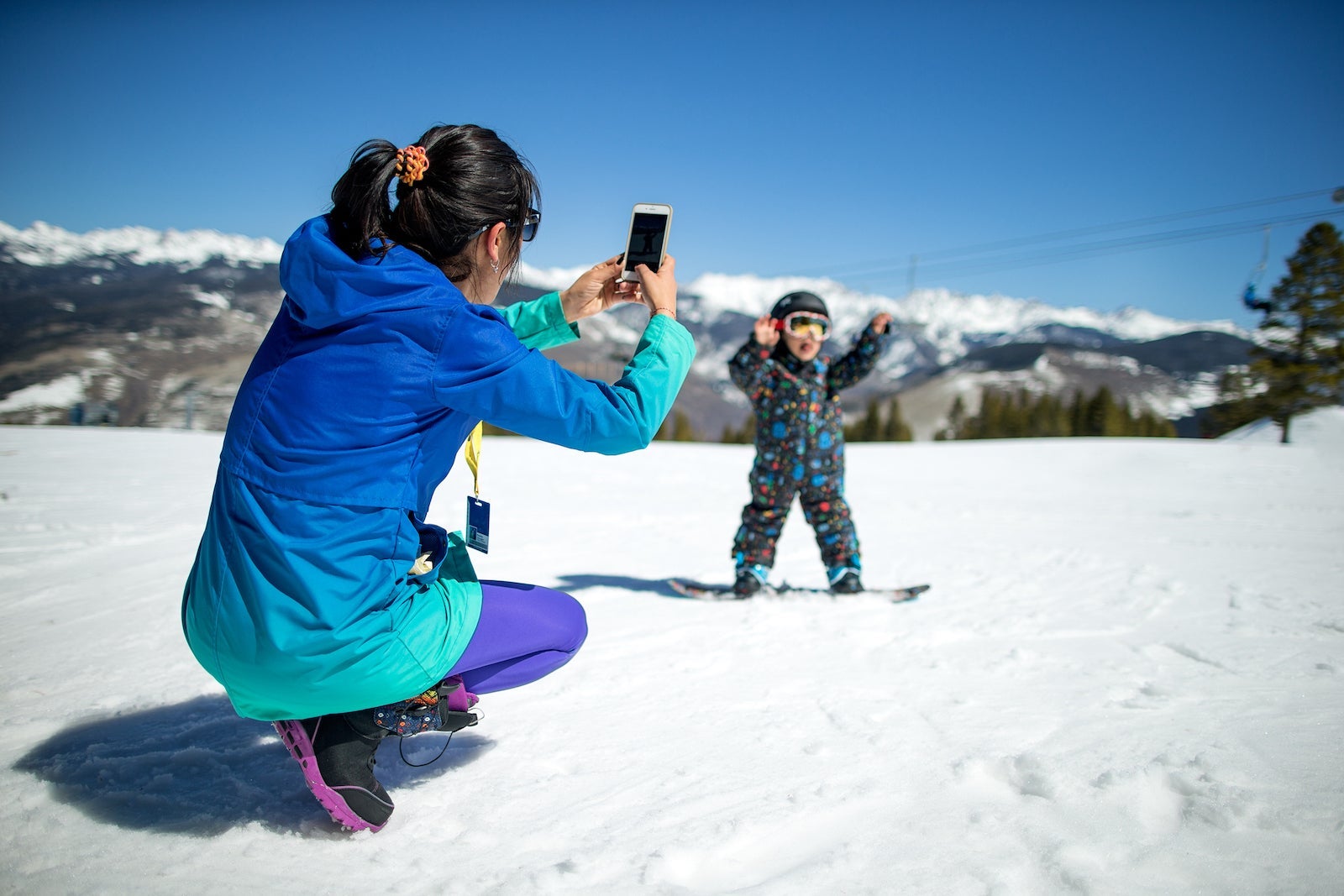 Mother taking photo of her son snowboading.