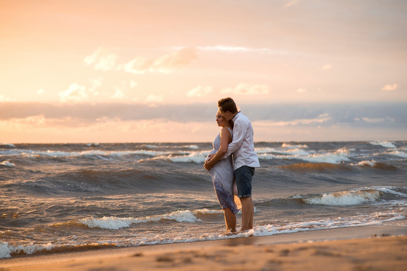 Couple Standing On Beach During Sunset