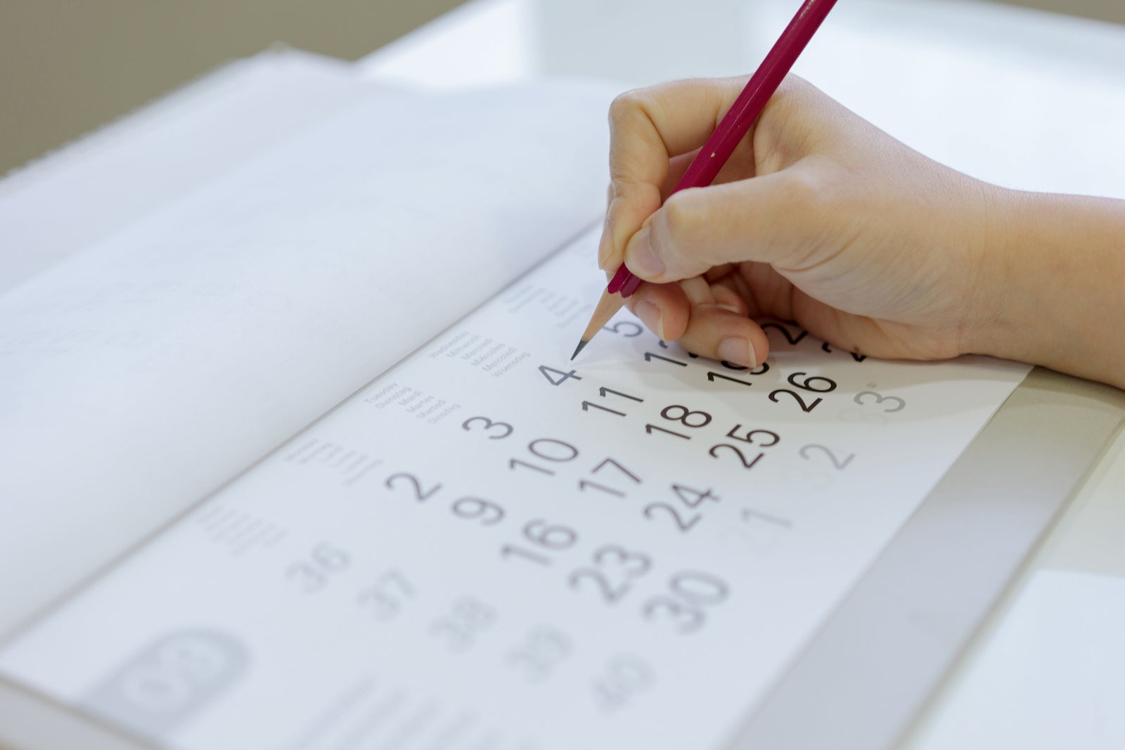 Cropped Hand Of Person Writing In Calendar With Pencil