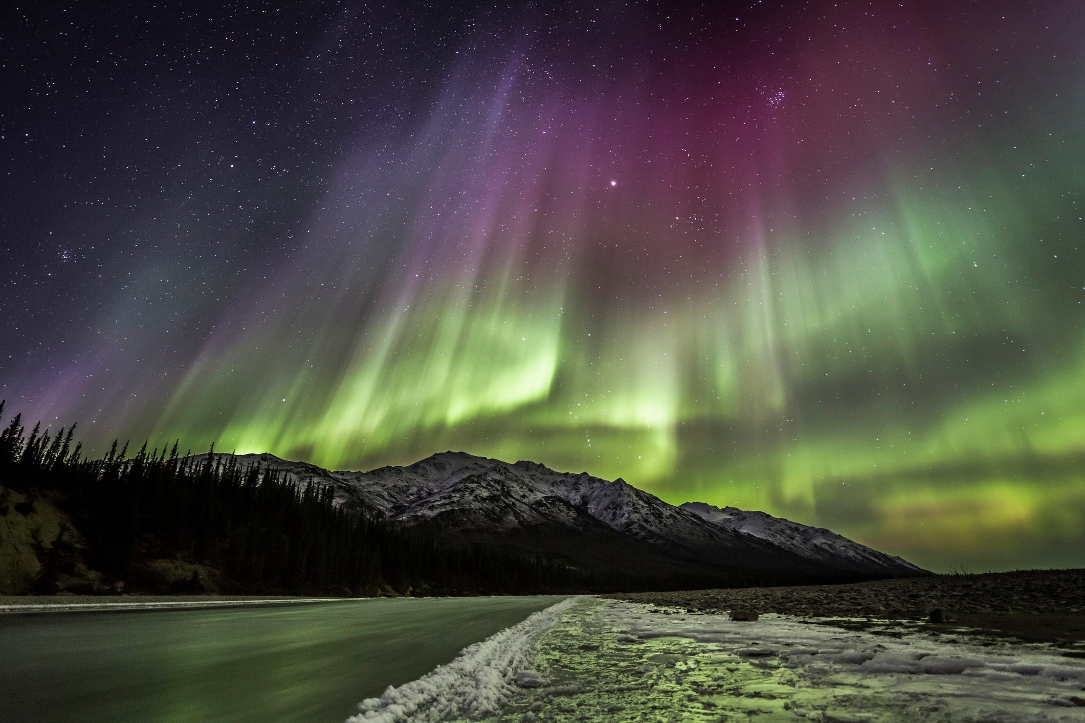 The aurora borealis reflects on the icy surface of a river in Alaska's Brooks range.