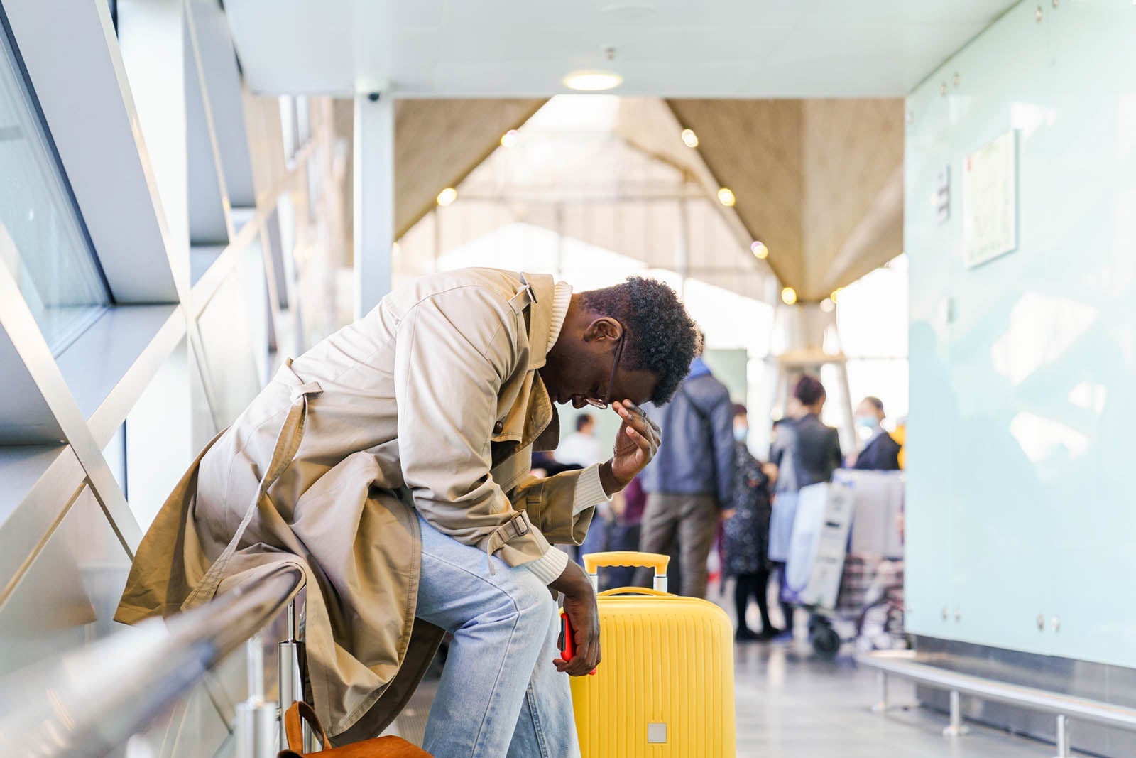 Black traveler man overslept his flight, missed the plane sitting in airport terminal. Side view.