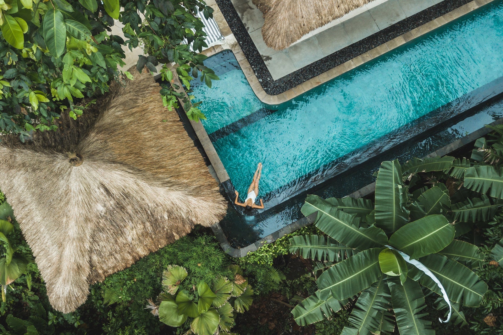Woman enjoying alone in luxury swimming pool, drone view from above