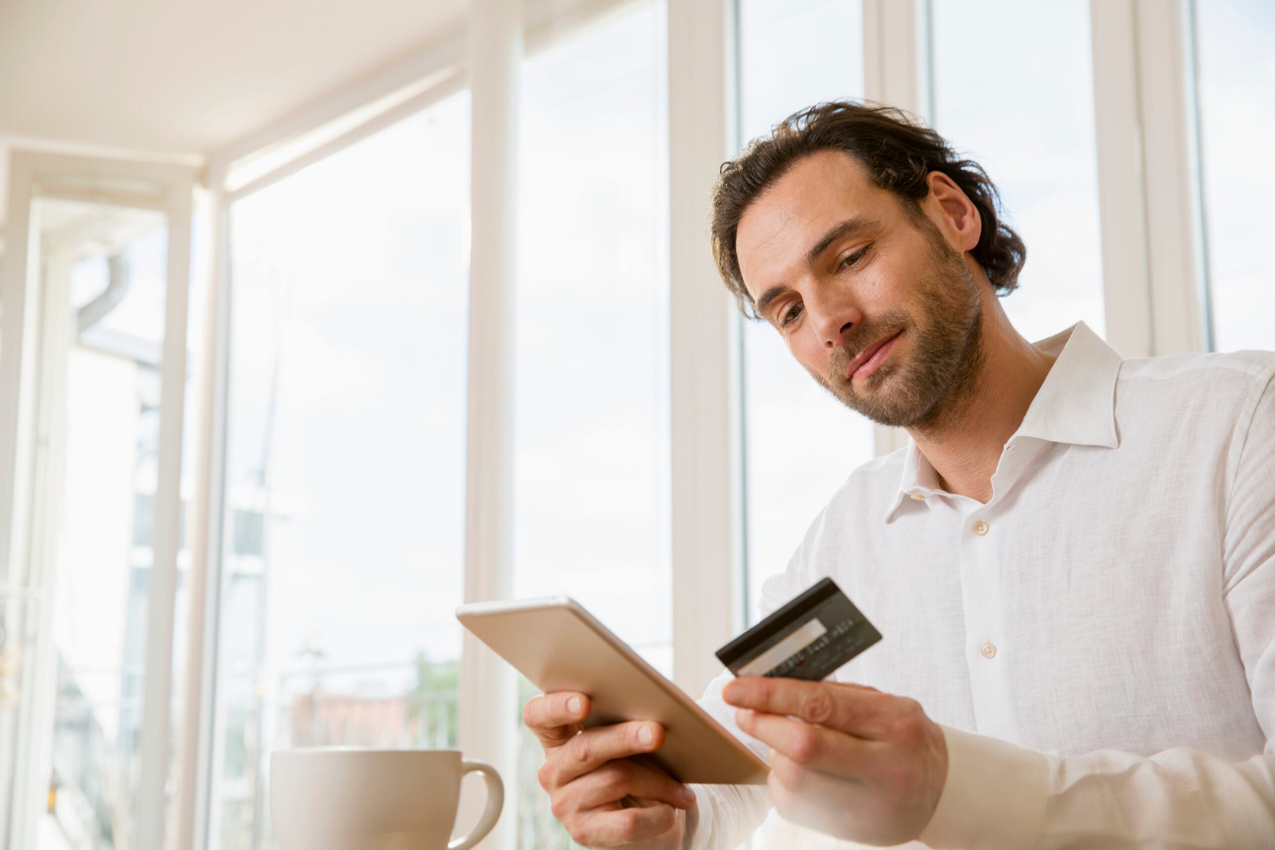 Portrait of man using digital tablet and credit card in office