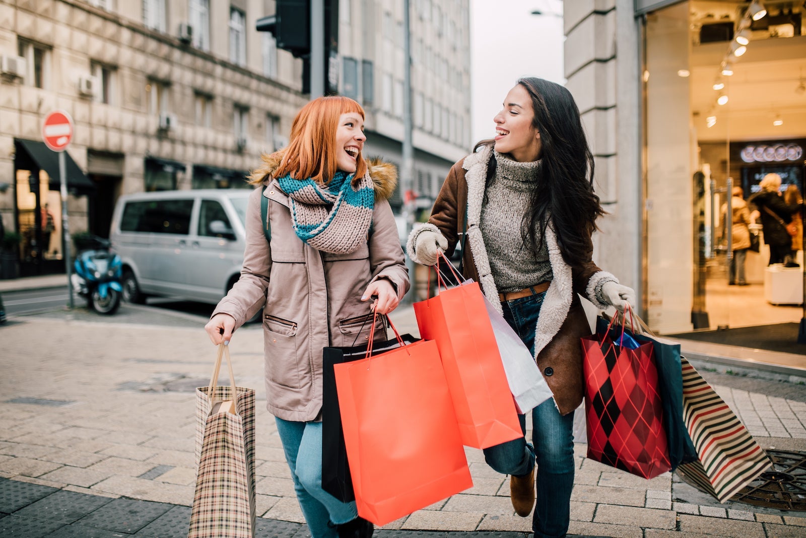 Two people walking on a street with shopping bags