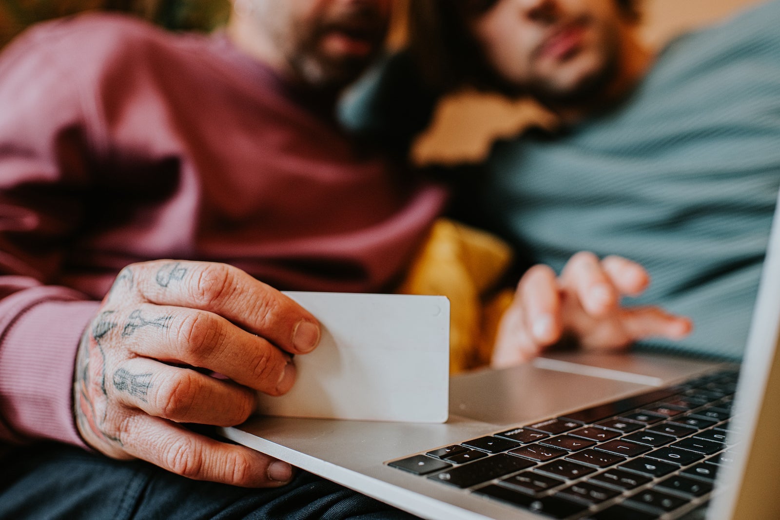 Close-up of a man holding a credit card as he shops online with his partner