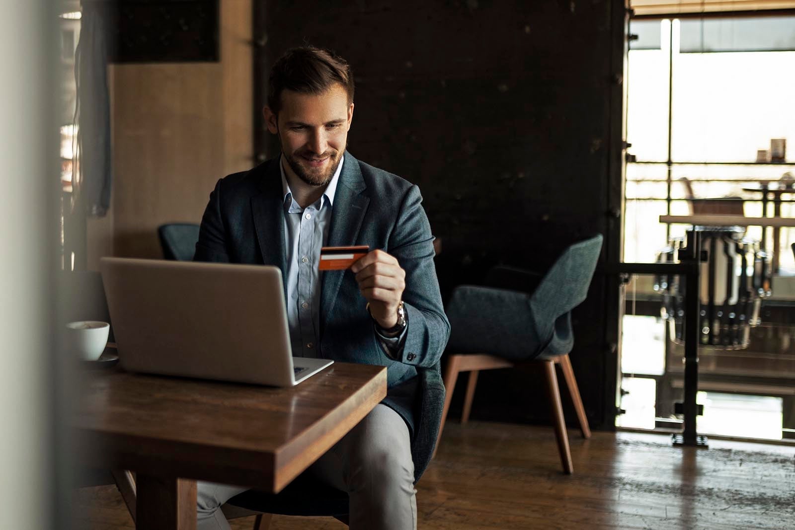 Smiling businessman holding credit card while online shopping