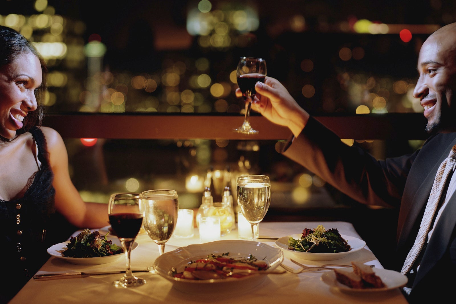Man toasting woman at restaurant table, side view