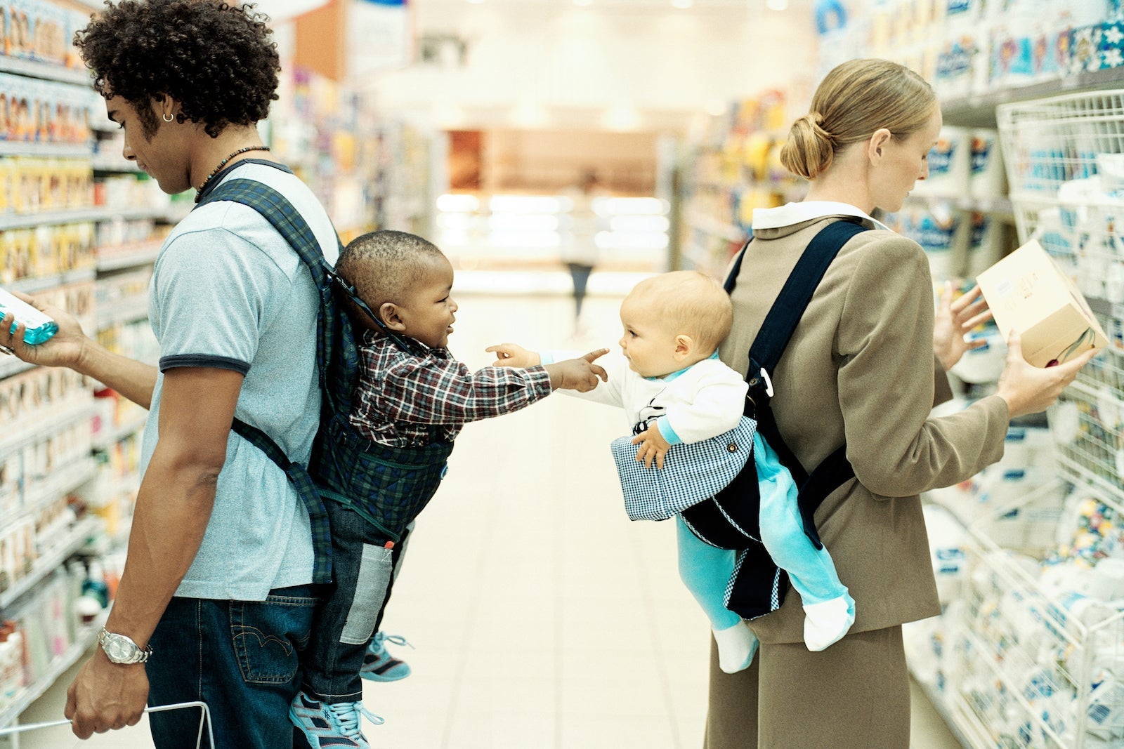 Baby boy and girl (9-15 months) in baby carriers, pointing, profile