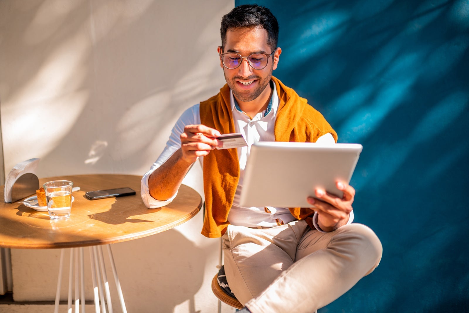 Young man sitting at cafe and using credit card to pay