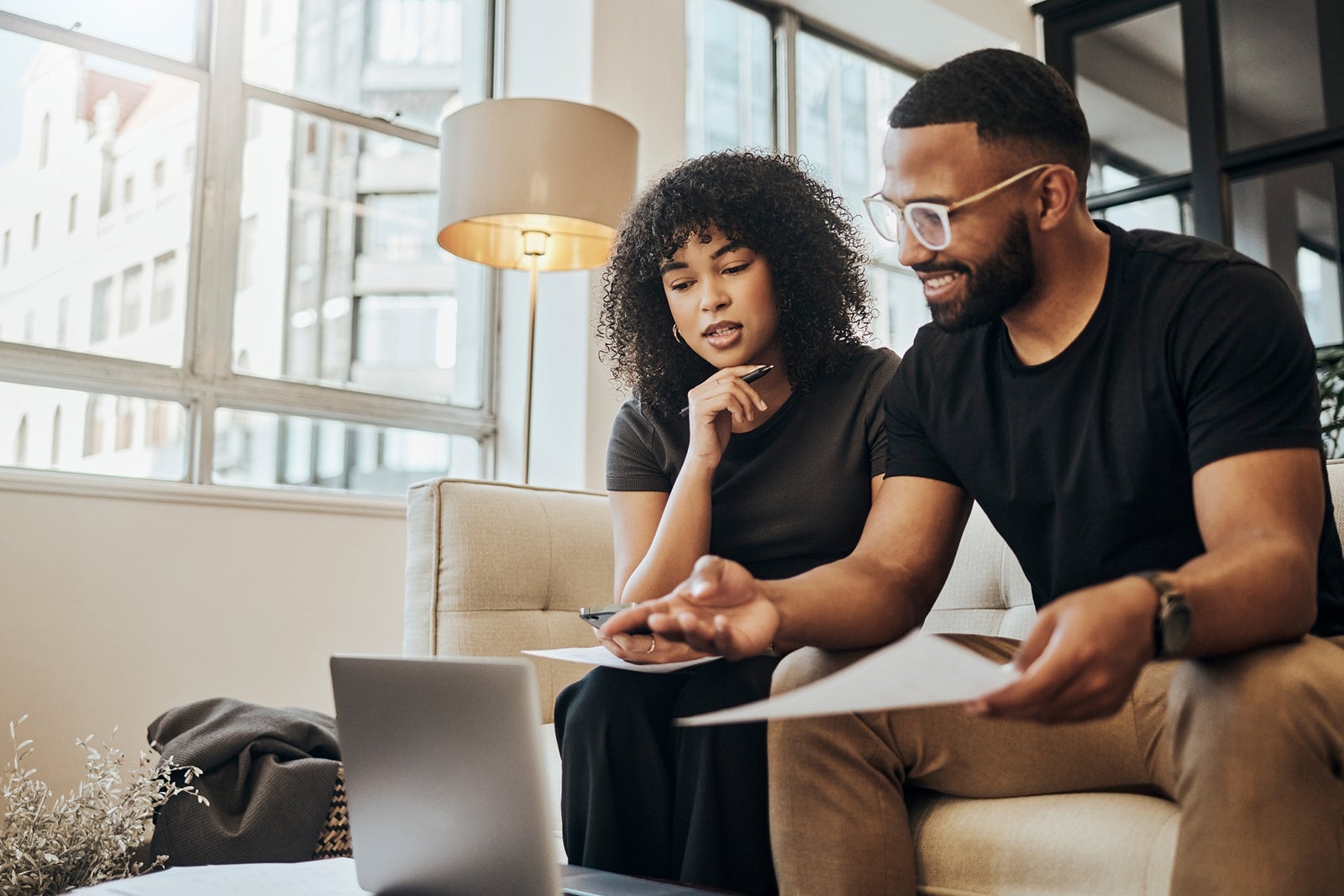 Finance, account and black couple with laptop on sofa doing online banking. Bills, budget and black man and woman with documents, paperwork and computer doing banking, payment and check bank account