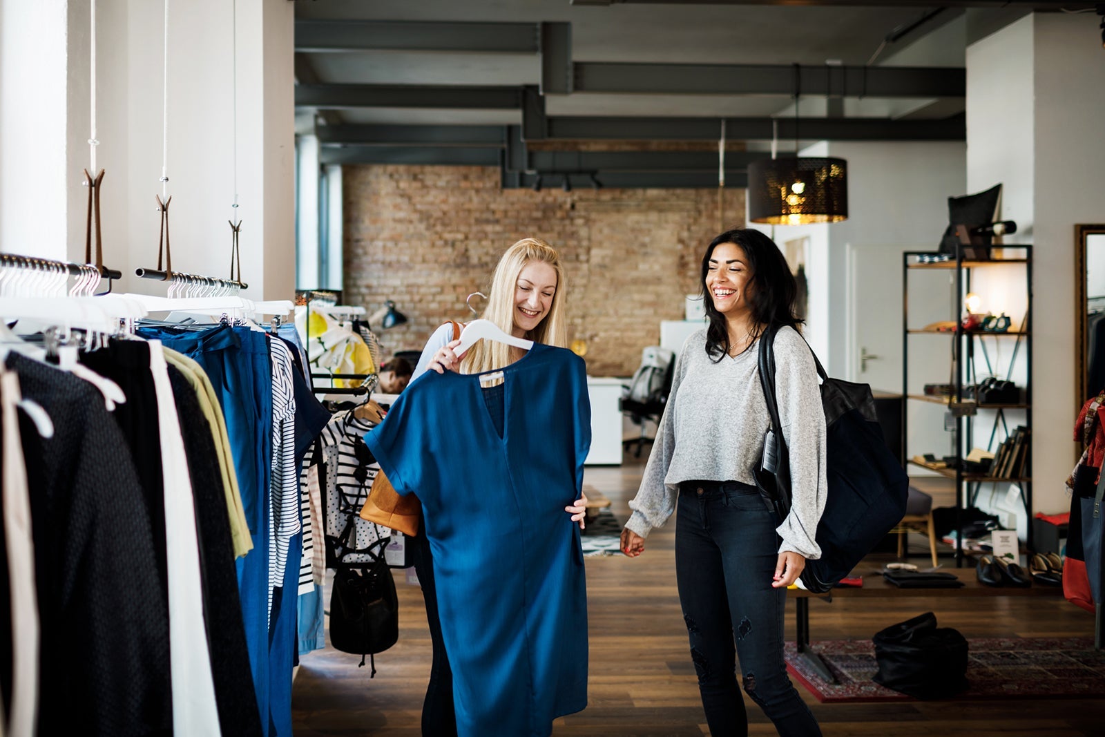 Women Laughing While Browsing Dresses In Store