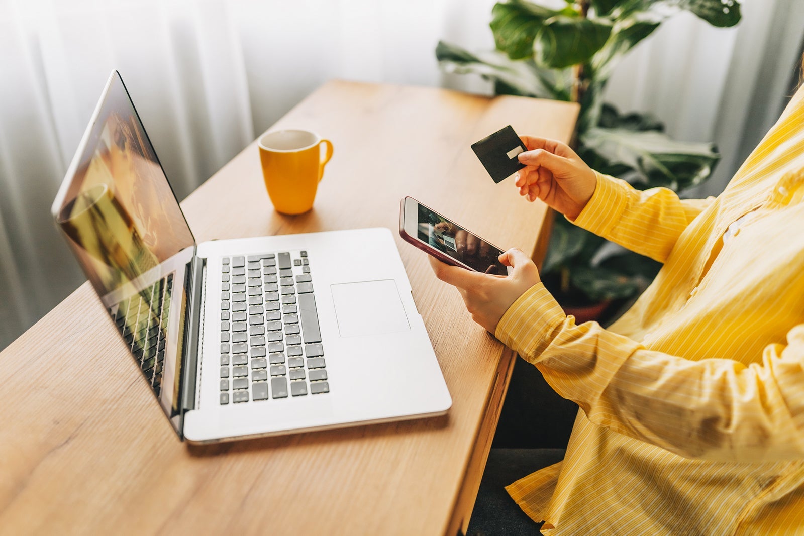 Shot of pretty young woman shopping online with credit card and laptop while sitting on the floor at home.