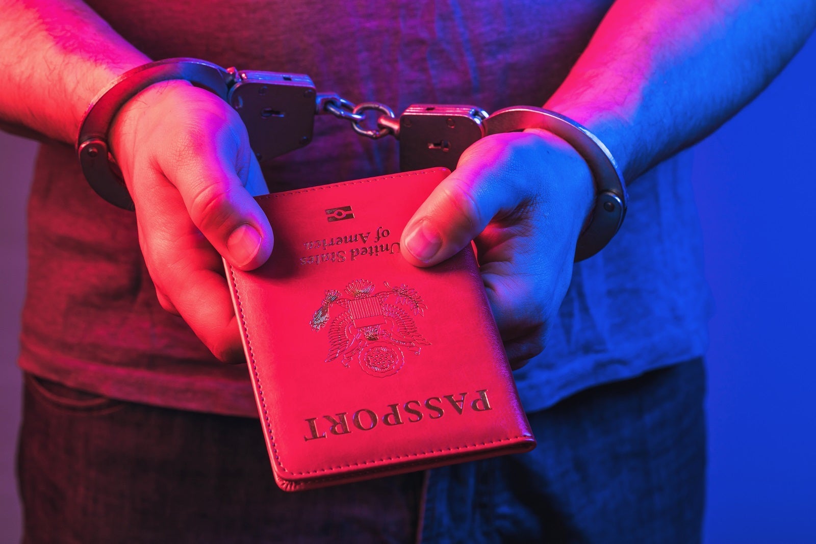 Hands in handcuffs with an American passport, the concept of punishment for fake documents