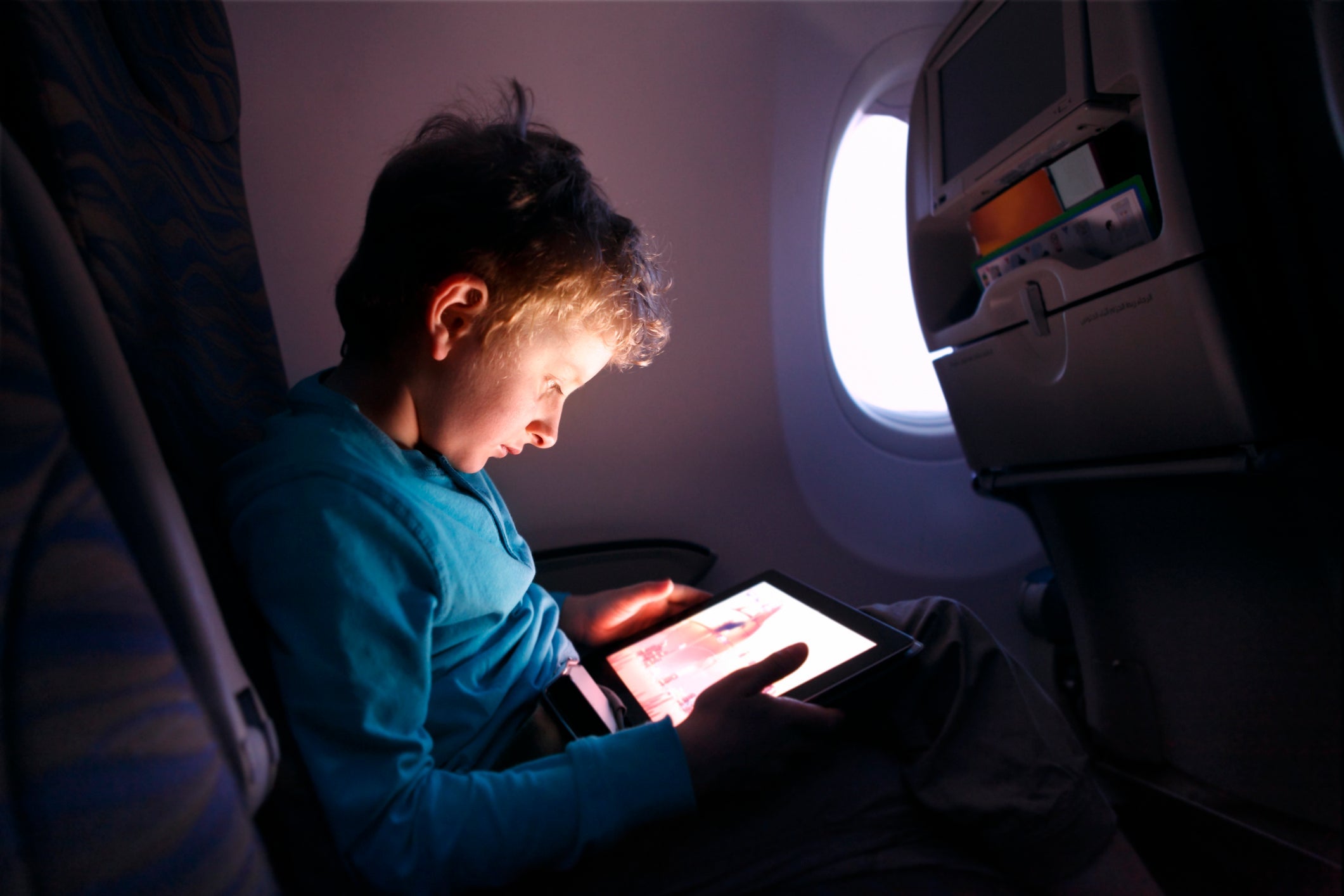 Little boy playing with tablet on the airplane