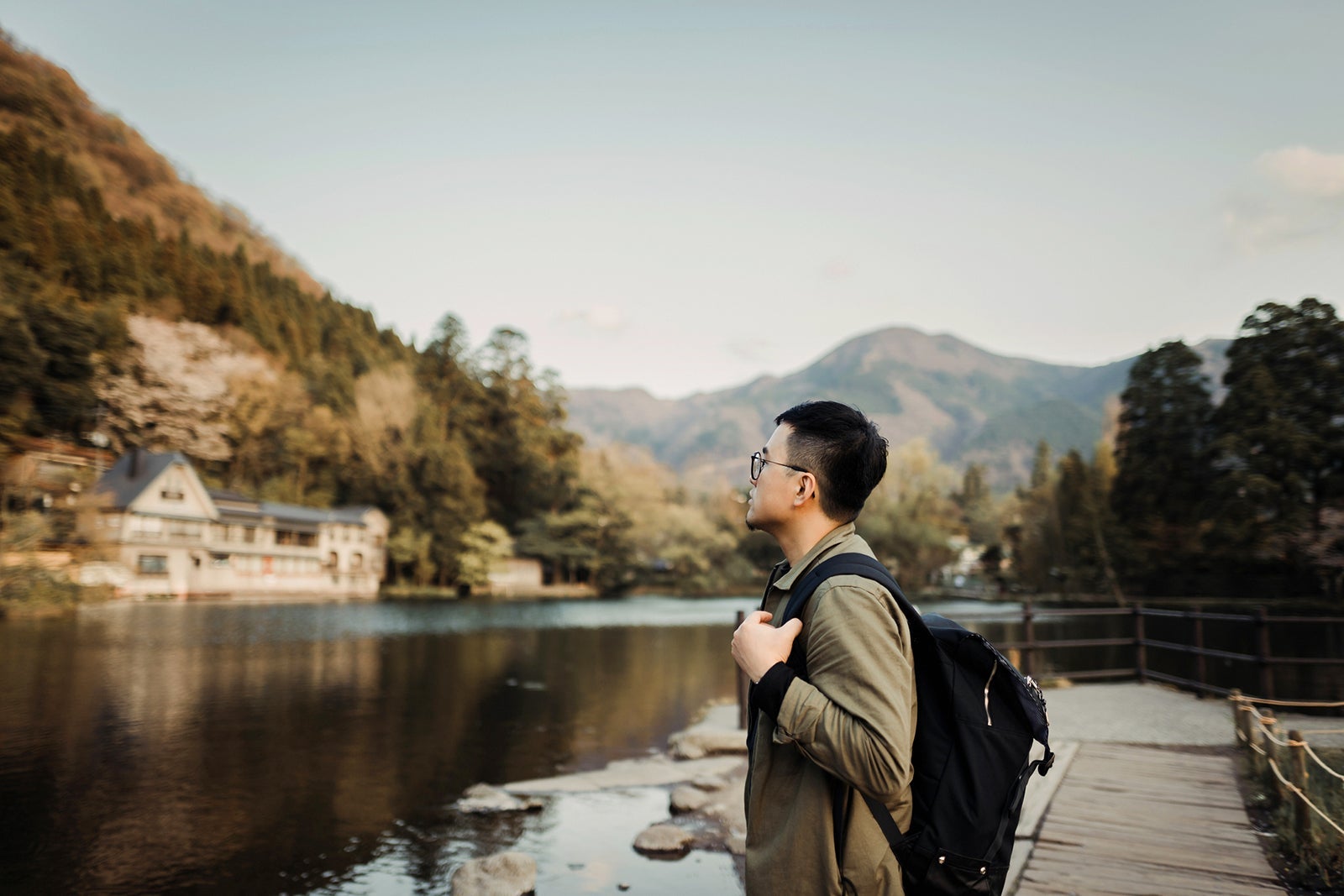 Young Asian man with backpack sightseeing at lake relaxing and enjoying the beautiful scenics