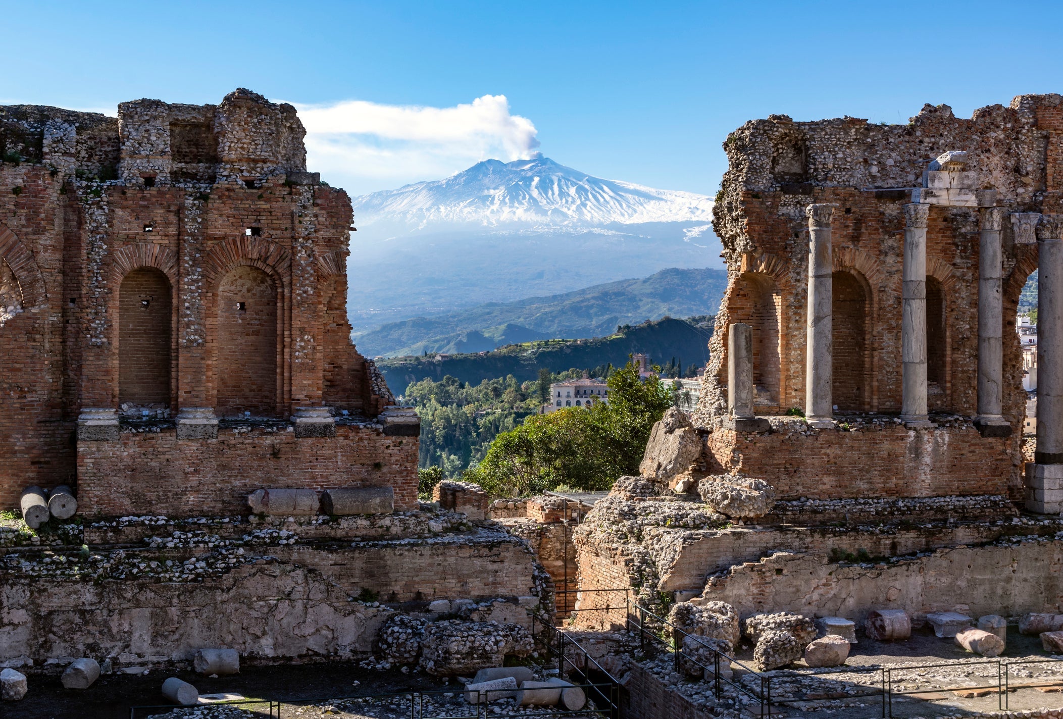 Volcano Etna in Sicily seen through ruins of ancient amphitheater in Taormina