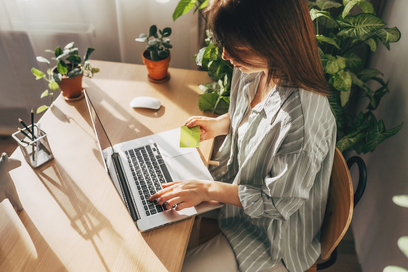 Young woman holding credit card and using laptop computer. Businesswoman working at home. Online shopping, e-commerce, internet banking, spending money, working from home concept