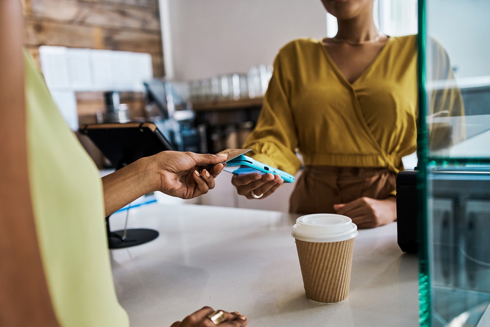 Contactless payment, NFC technology and tapping a credit or debit card at a counter to pay for coffee. Closeup of a woman buying a hot beverage at a cafe and using an online or wireless paying method