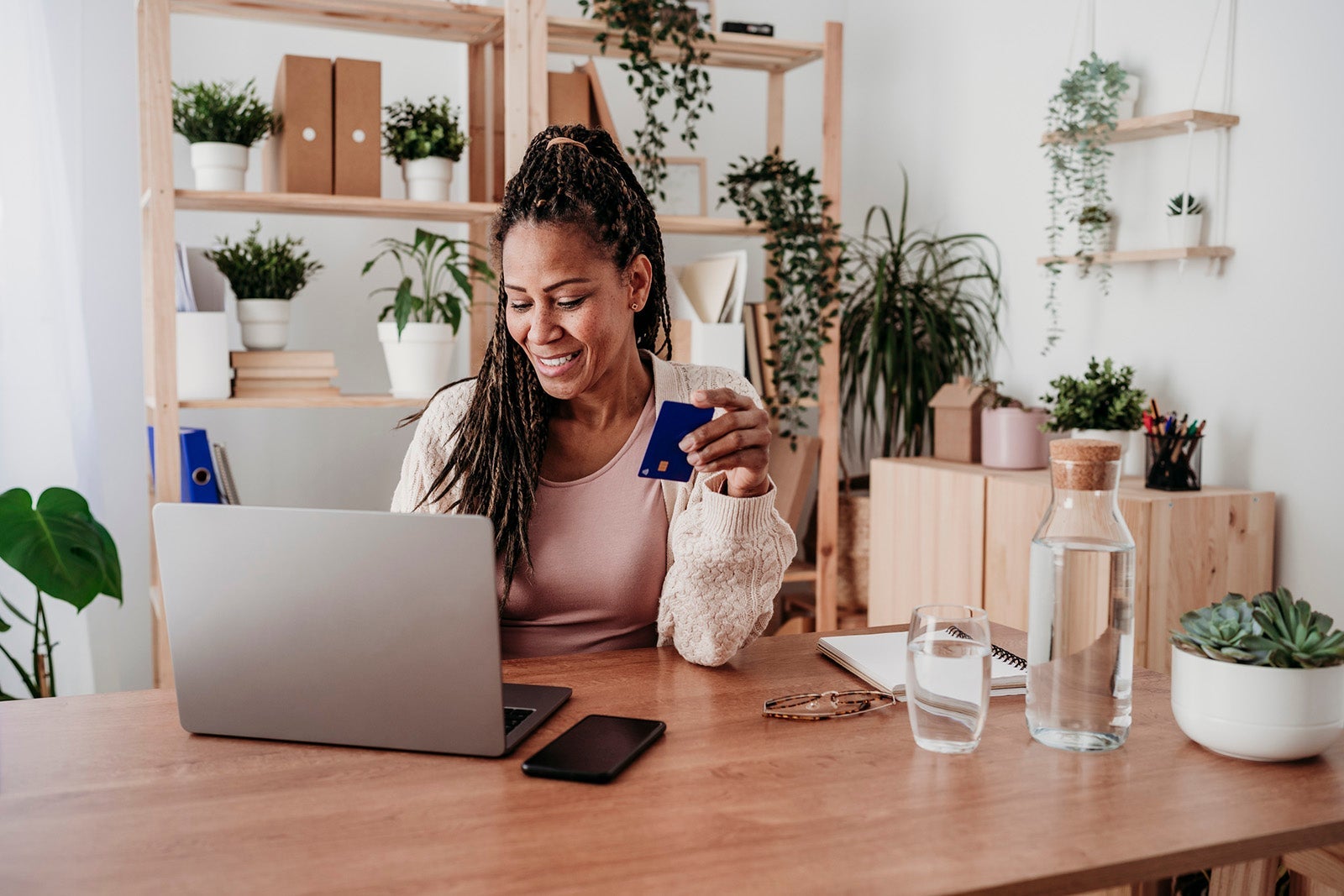 Smiling freelancer paying with credit card on laptop at home office