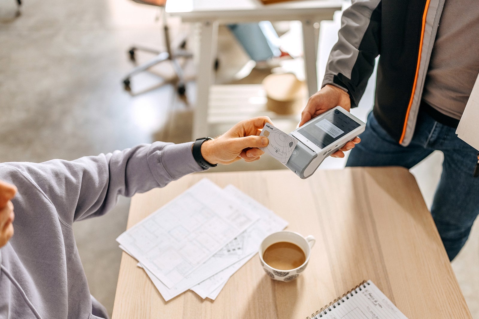 Close up of a man's hand paying delivery with credit card in a office, scanning on a card machine