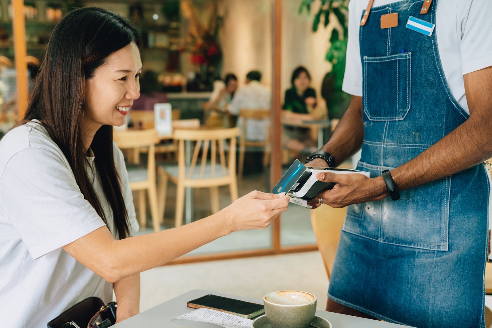 woman paying contactless with credit card in cafe