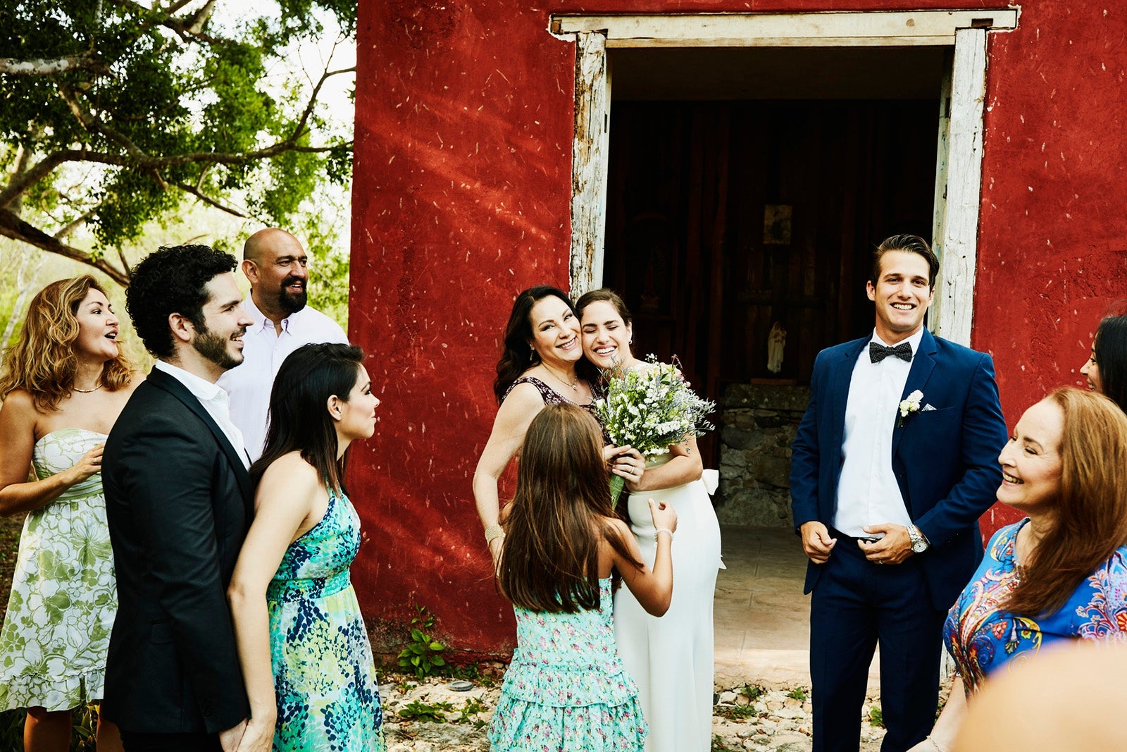 Smiling mother hugging bride after outdoor wedding ceremony at tropical resort