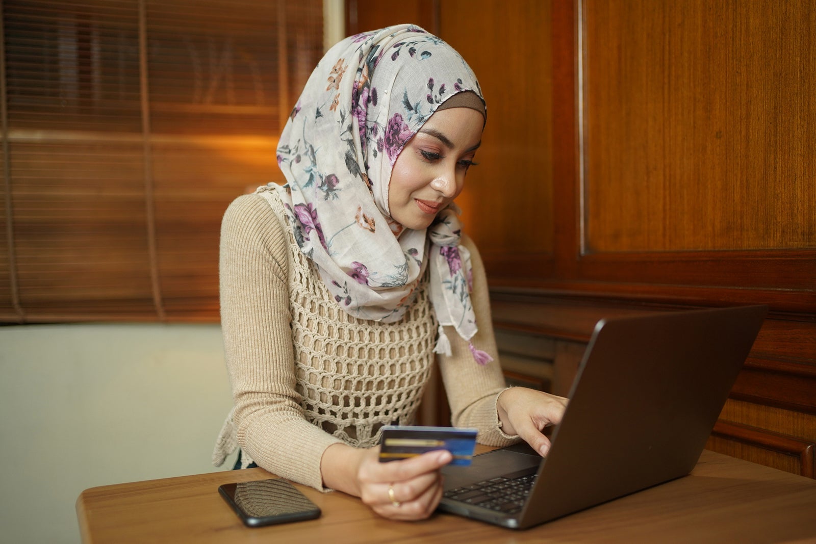 Asian Muslim woman holding a credit card and using the laptop for online shopping and online payment via the internet. Technology concept.