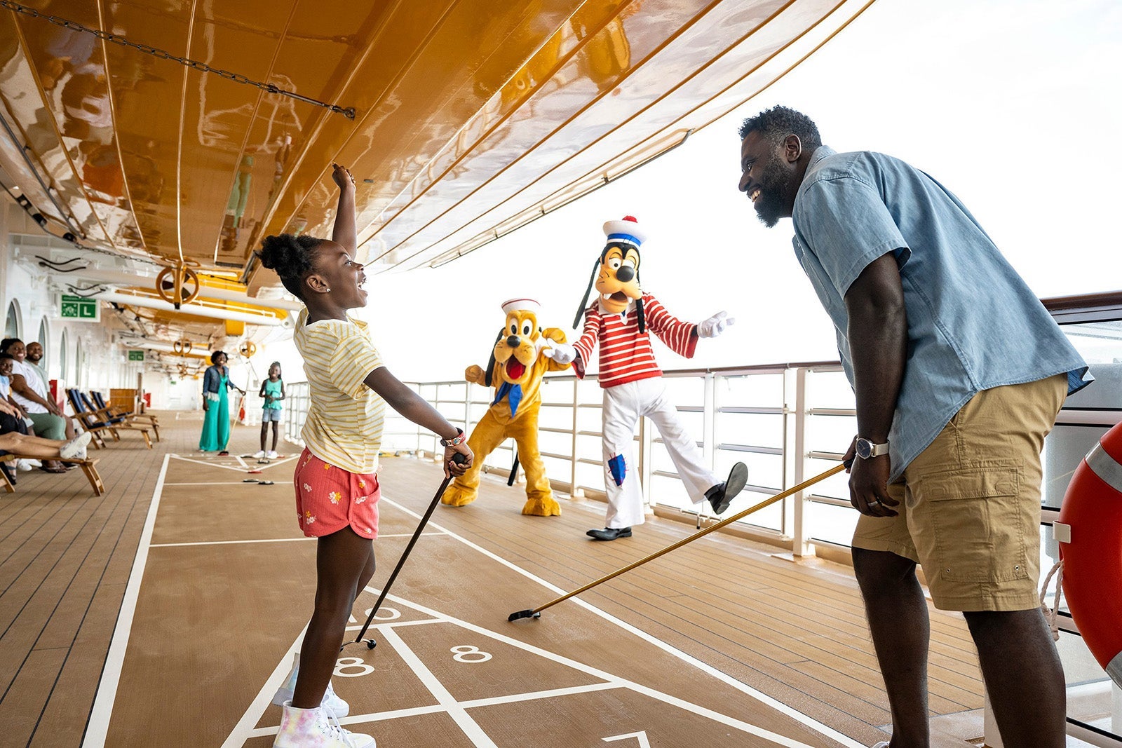 Characters on Disney Wish_Disney Cruise_Family playing shuffleboard on cruise