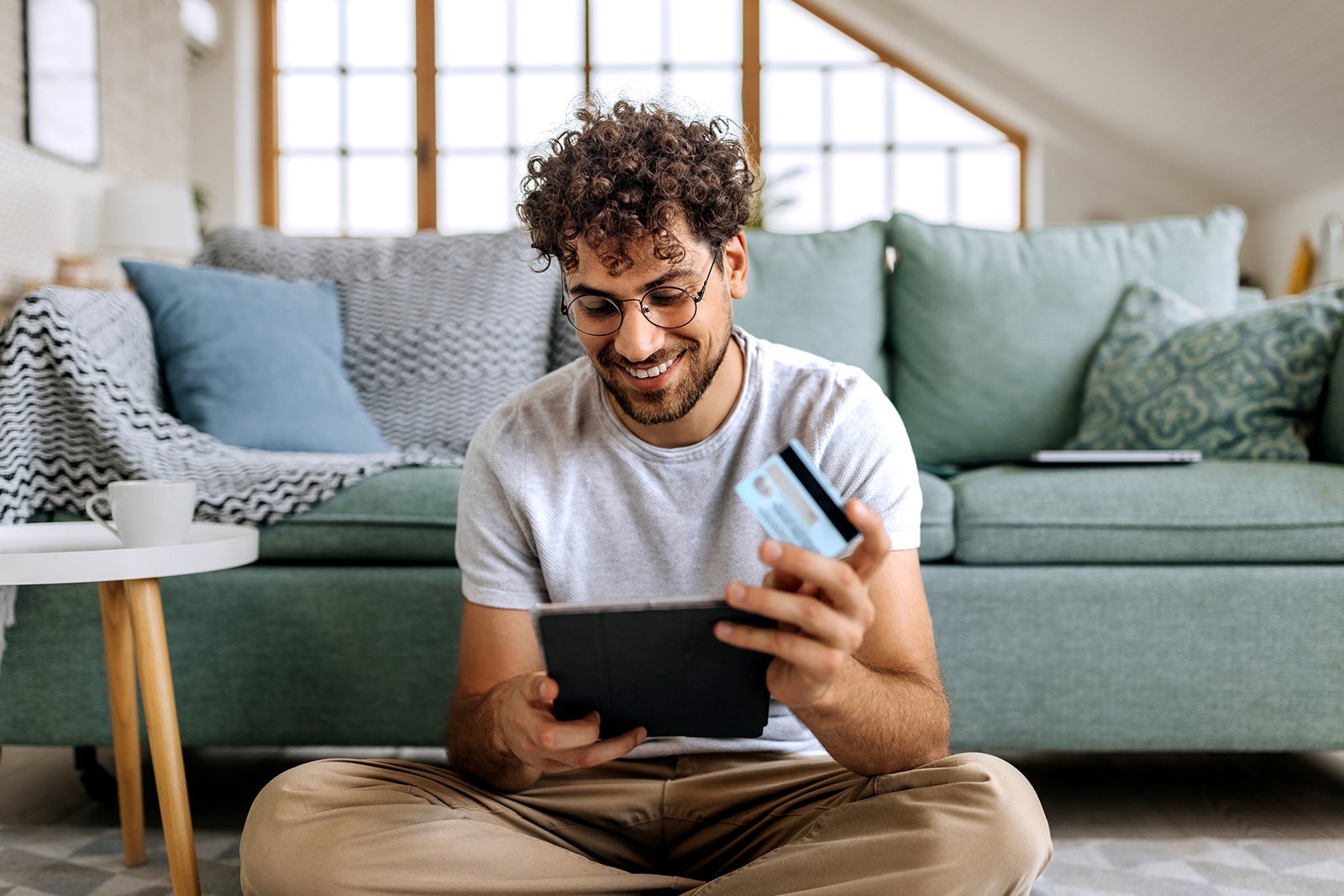 Young casually clothed man shopping online while sitting on a floor at home
