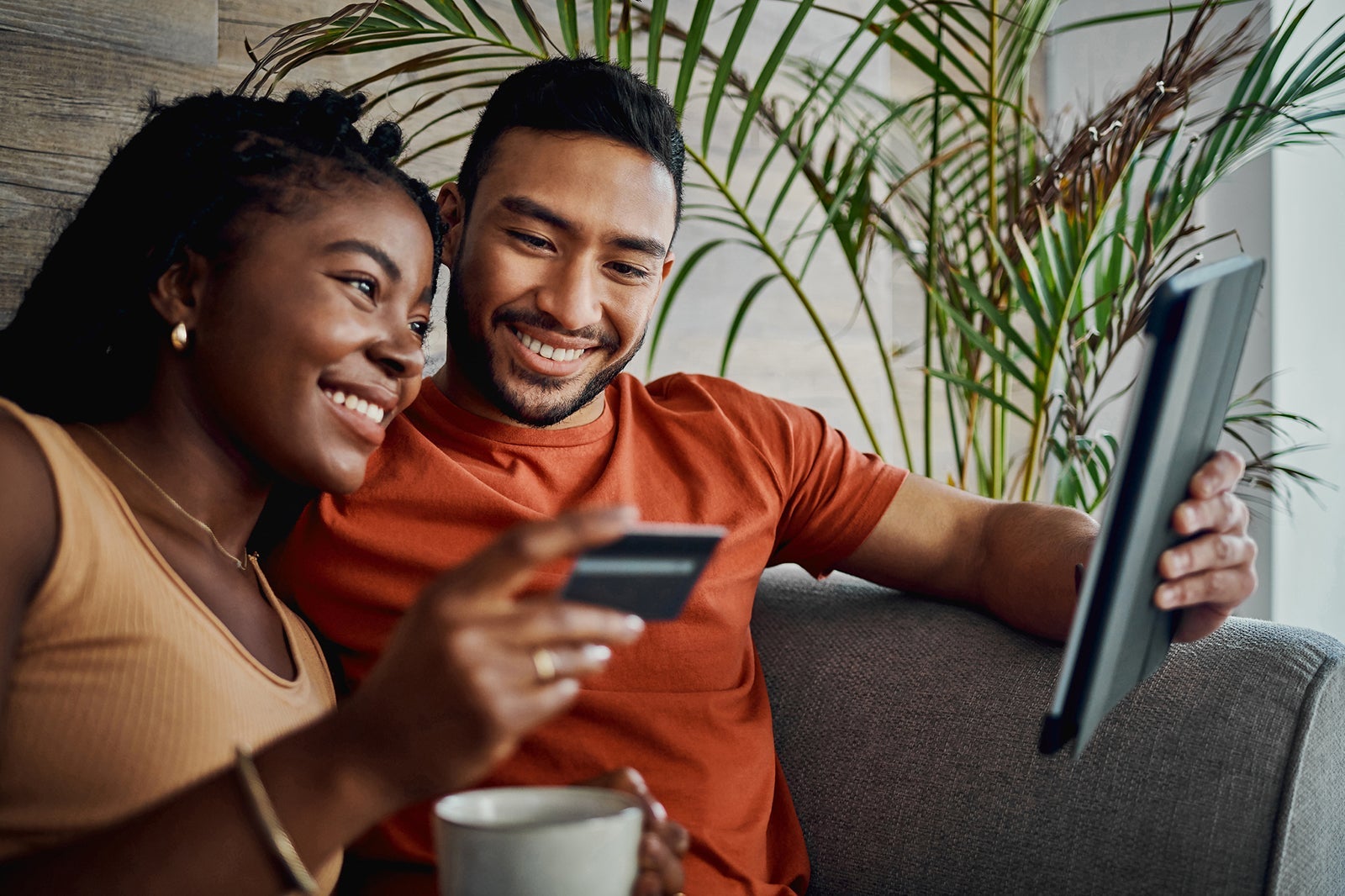 Shot of a young couple sitting together in the living room and using a digital tablet for online shopping
