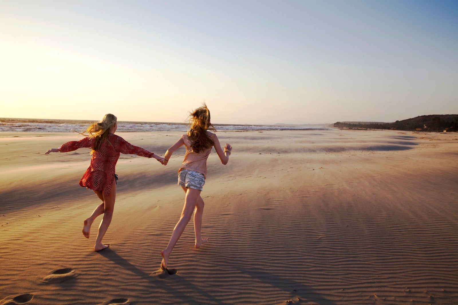 Mother and daughter running on empty beach