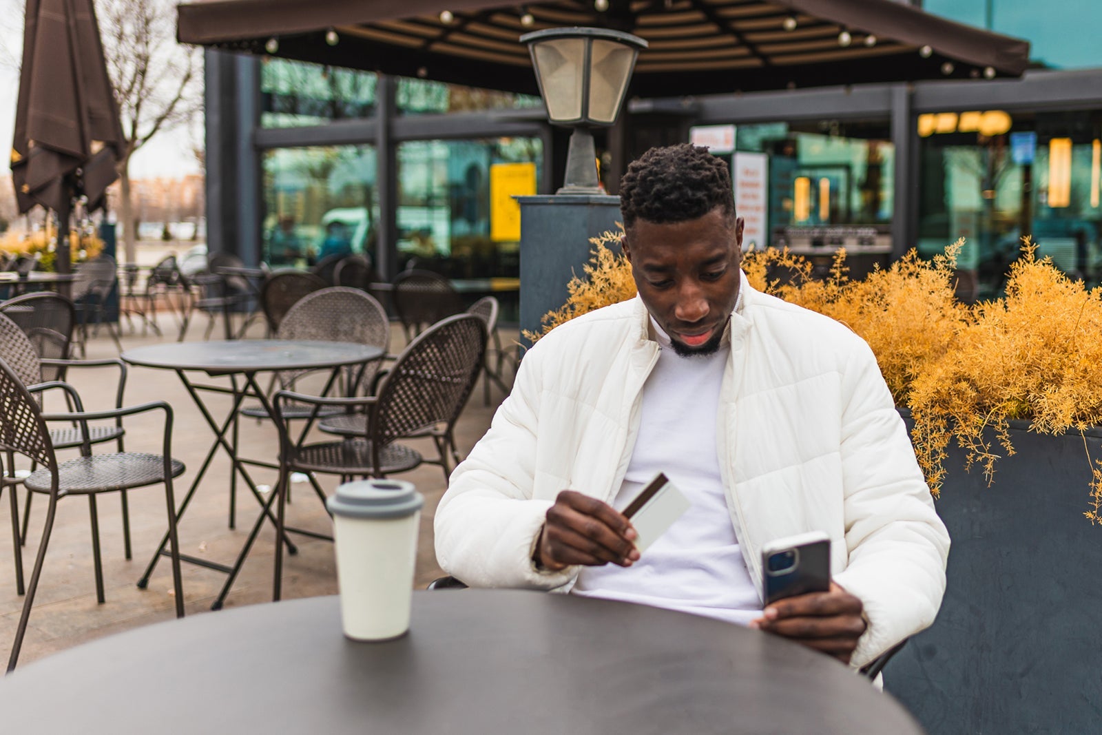 Multiracial man making payment with credit card, afro man with credit card and cell phone, young afro man looking at cell phone with credit card