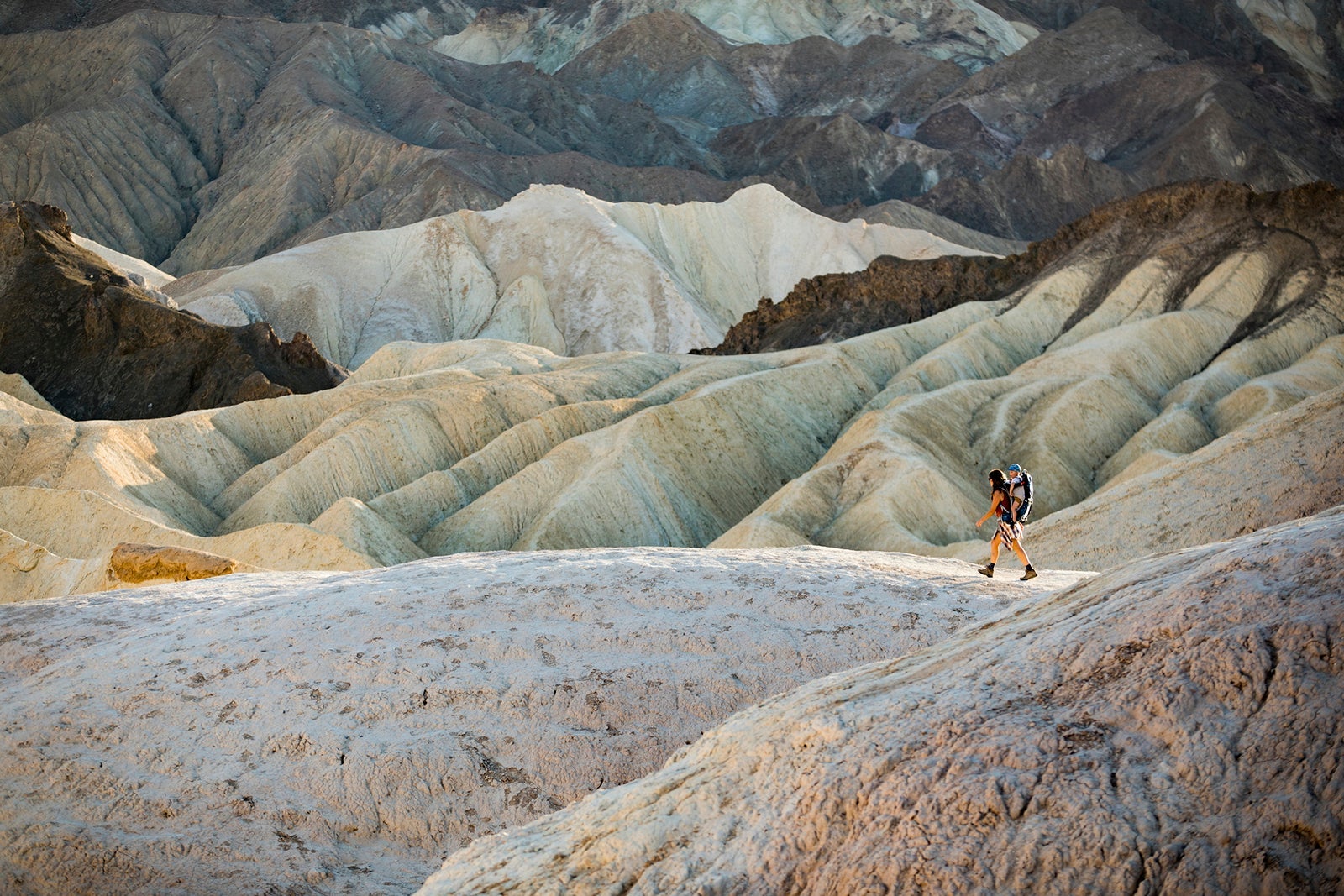 A woman and her son hiking through dramatic mountains in Death Valley
