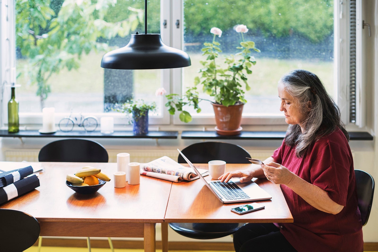 Side view of senior woman using credit card for online shopping at home