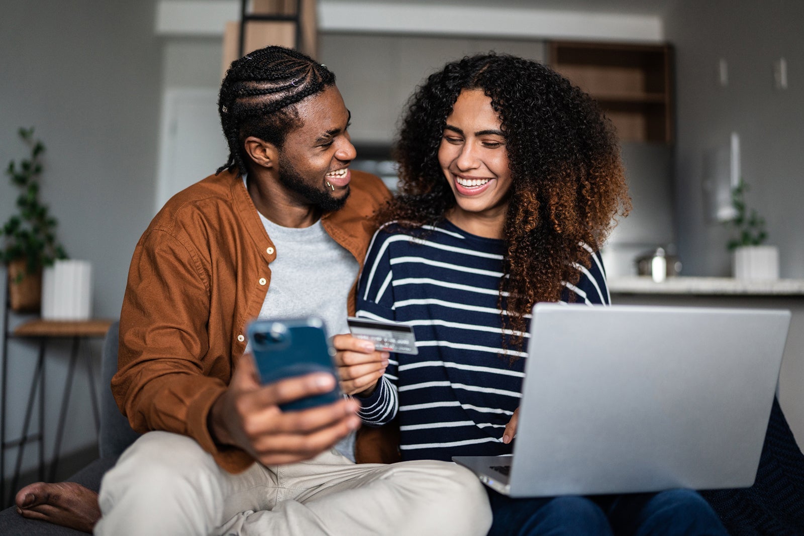Young couple online shopping using mobile phone and laptop at home